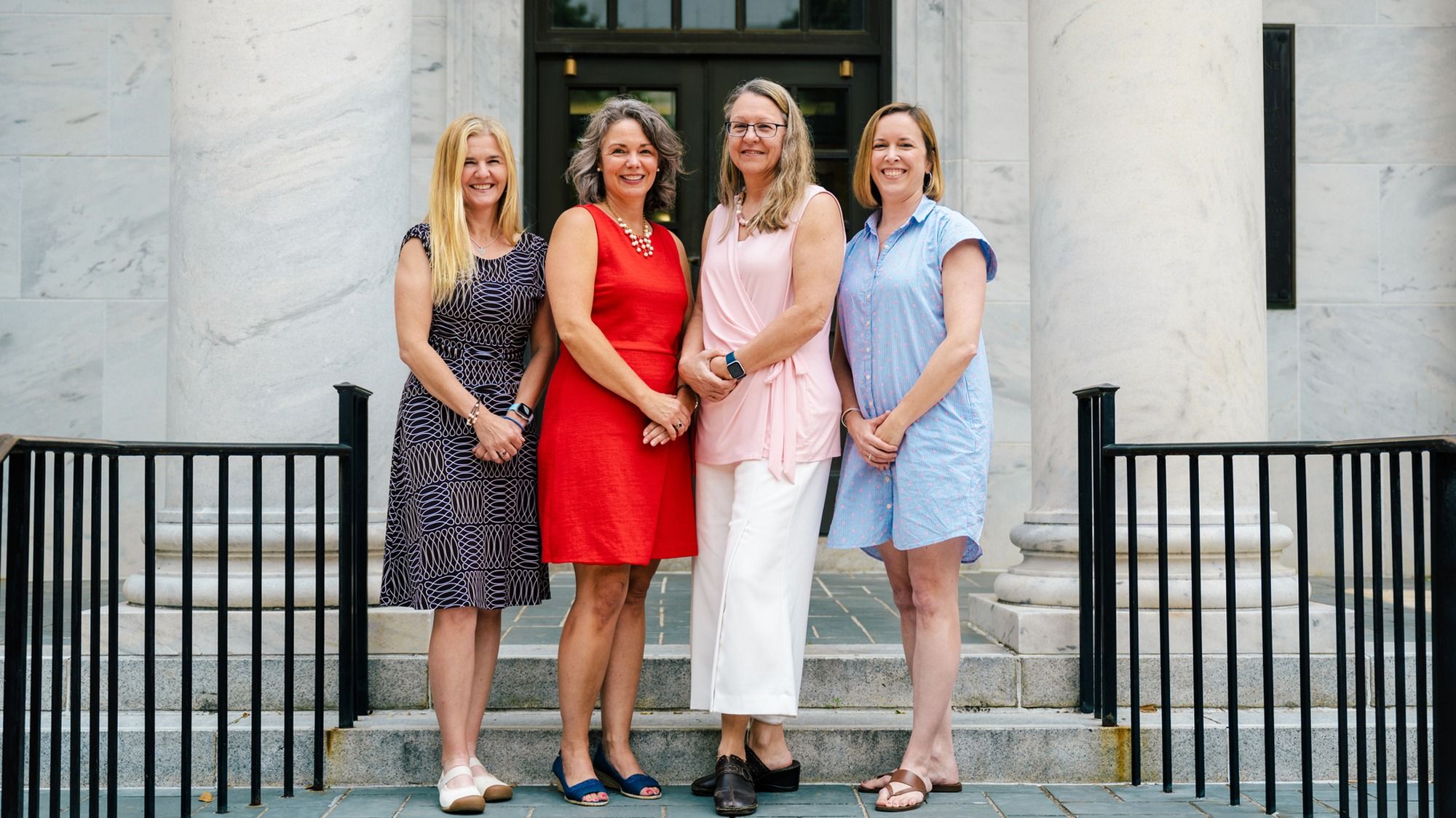 Leerkes, Shriver, Wideman, and Dollar of iGrow study standing together outside a building with large stone columns and black railings, posing on a stone walkway in front of a dark doorway.