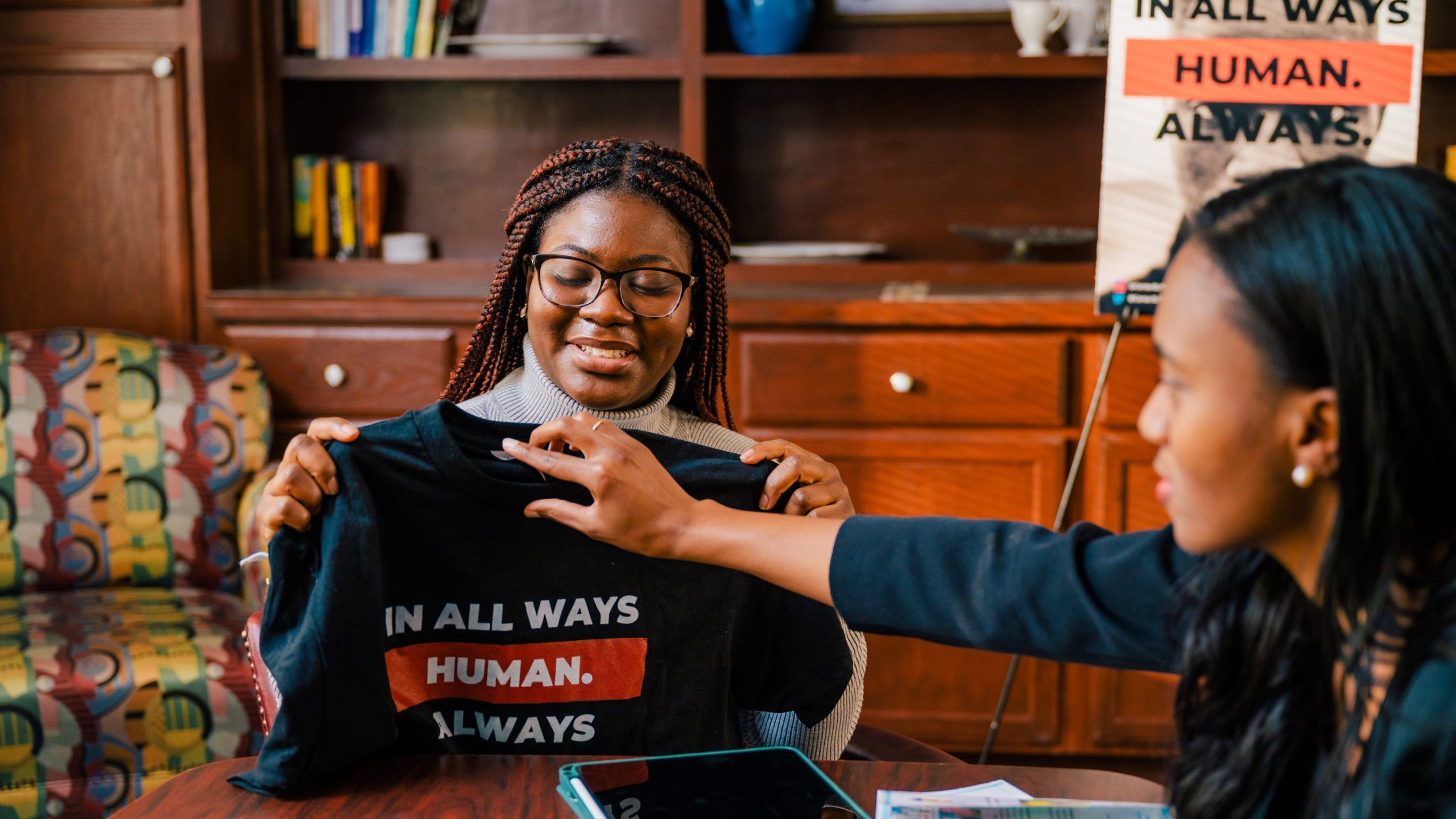 Doctoral student Youselene Beauplan holds a shirt that says "In All Ways Human. Always"