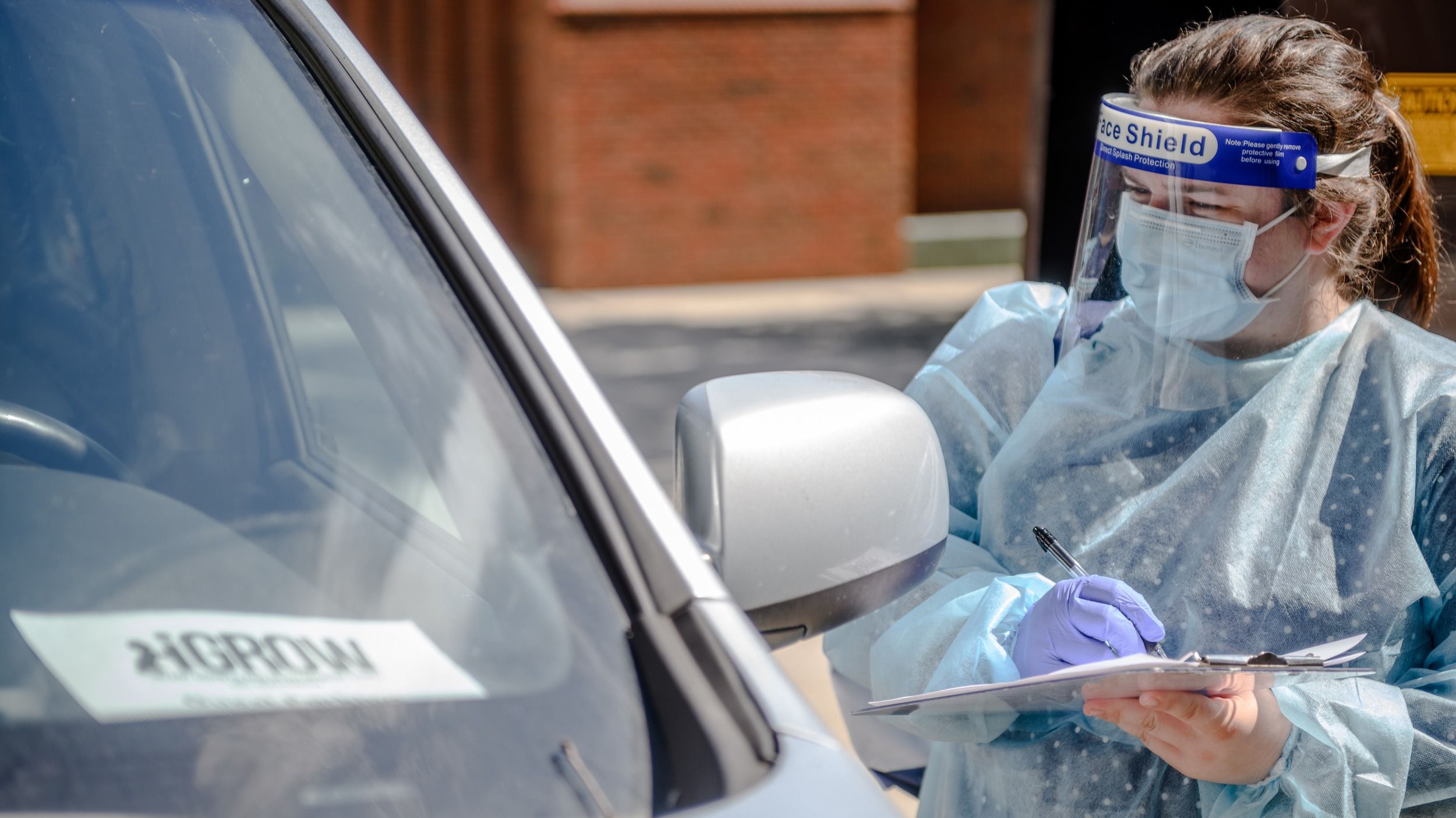 A researcher wearing protective material in July of 2020 at the car of a participant