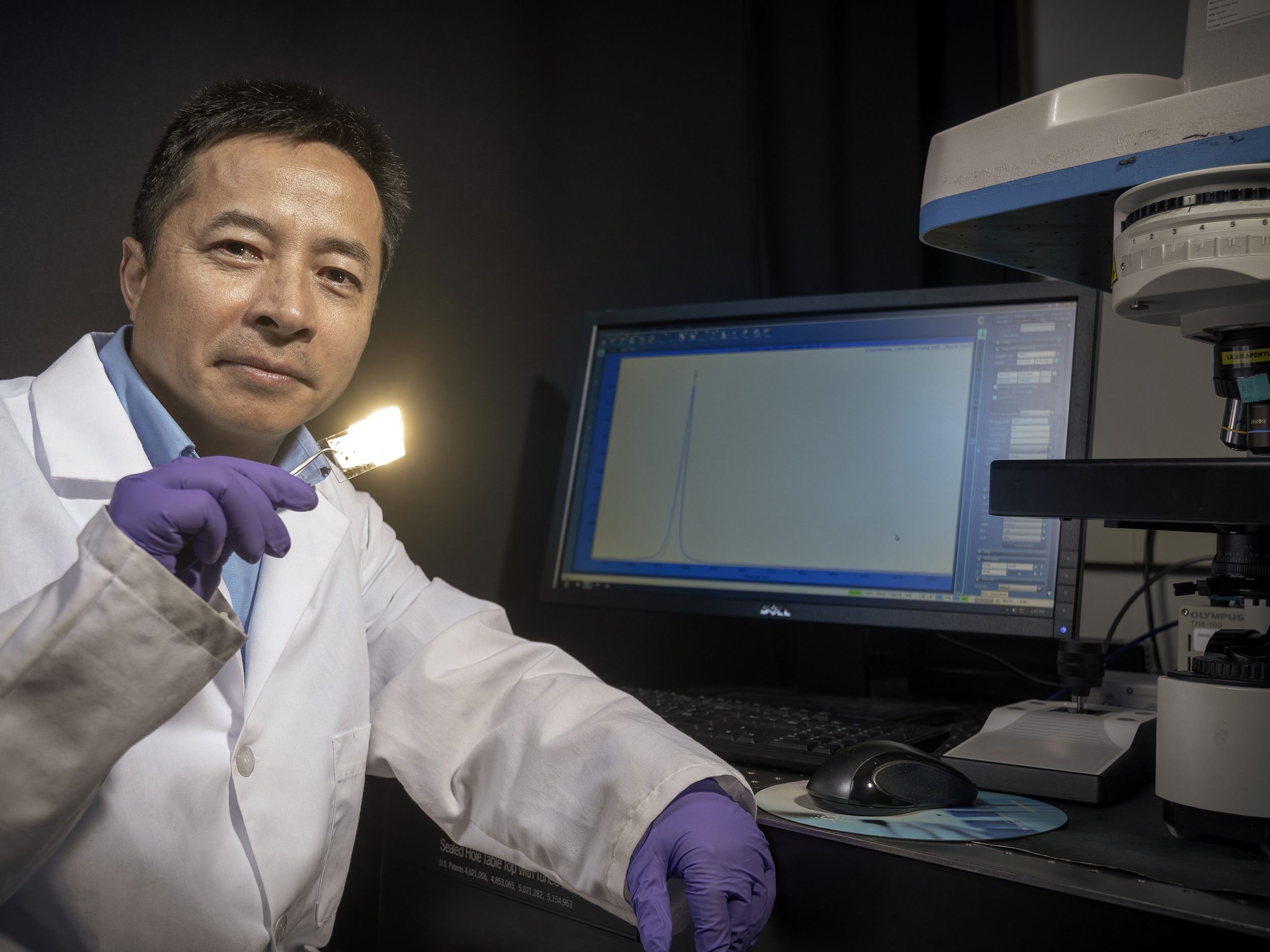 Dr. Jianjun Wei holds up a device he has been working on to detect heart attacks.