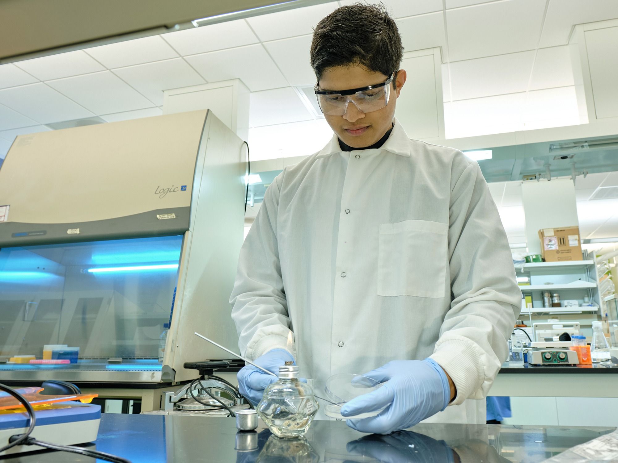 Graduate student Parth Desai works with a small flame and a bacteria sample in the lab.