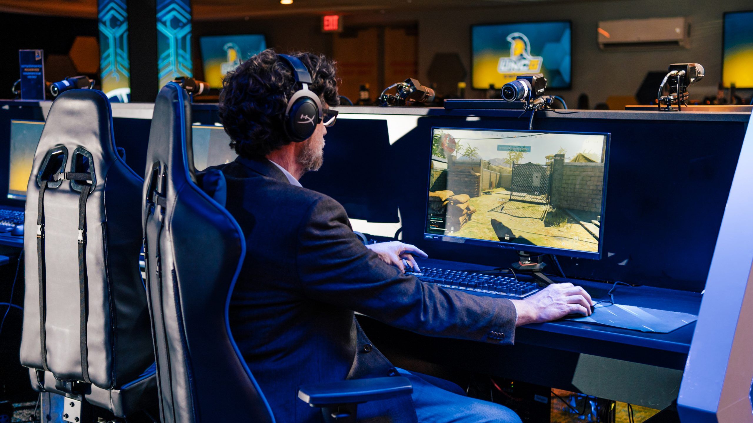 Dr. Grieve sits in UNCG's E-Sports arena playing a video game.