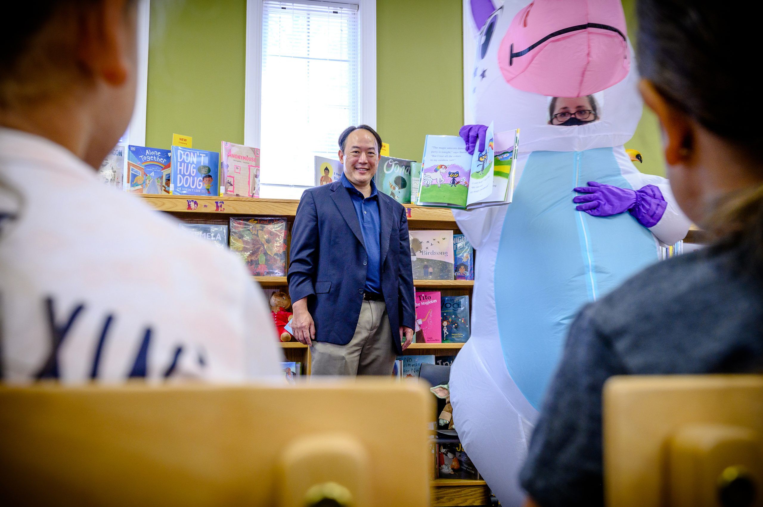 Anthony Chow and the unicorn mascot standing in front of children