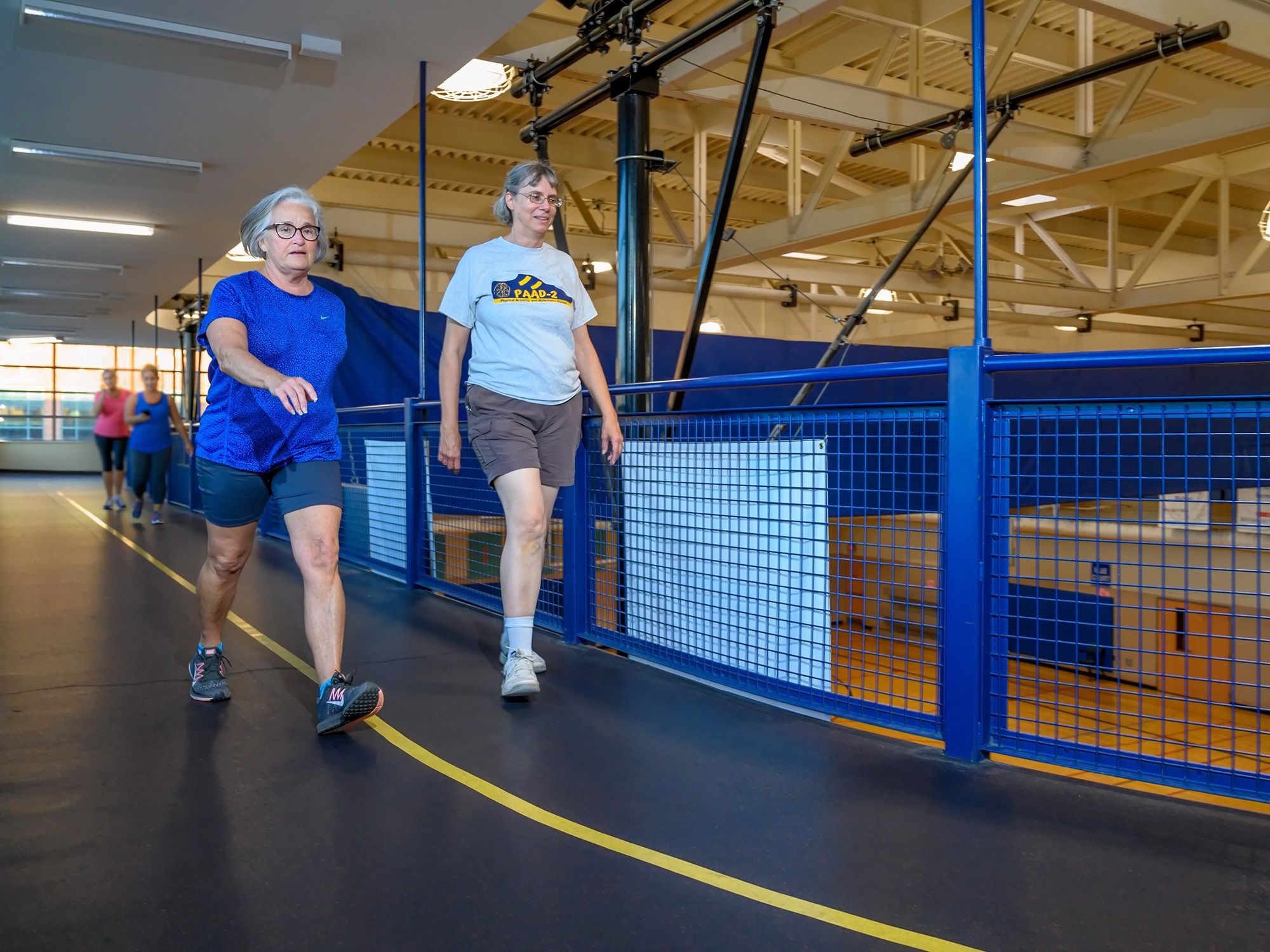 Two research participants walk around an indoor track.