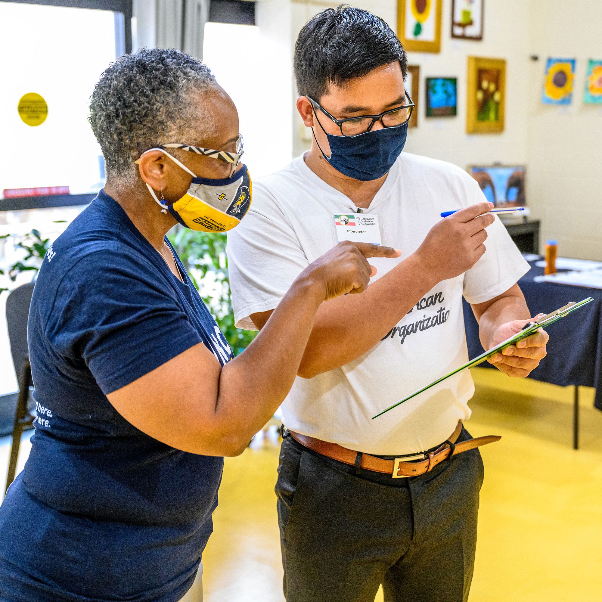 Dr. Morrison and Xuem Siu examine a clipboard at a vaccine clinic.
