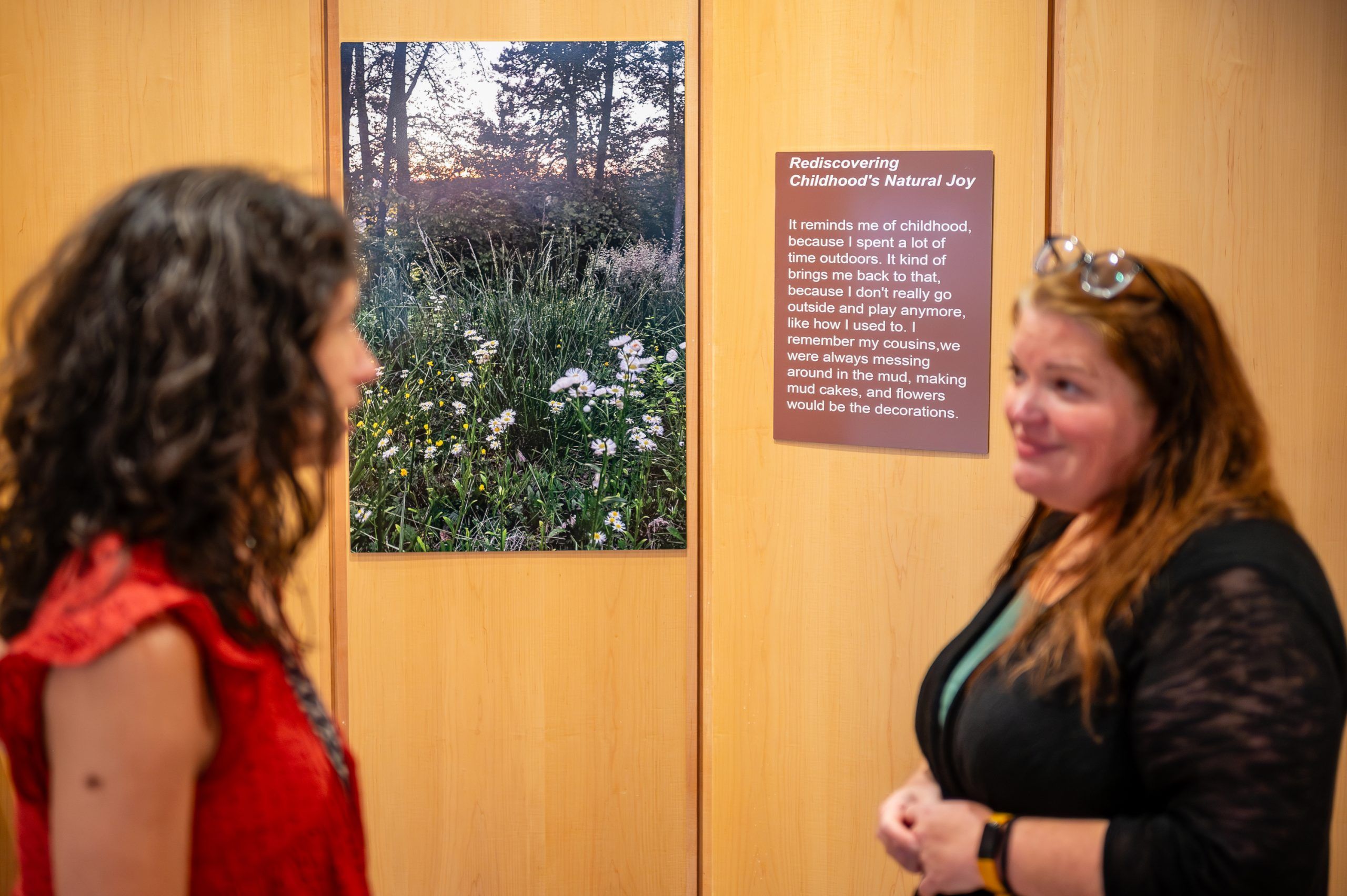 A student standing near the work "Rediscovering Childhood's Natural Joy"