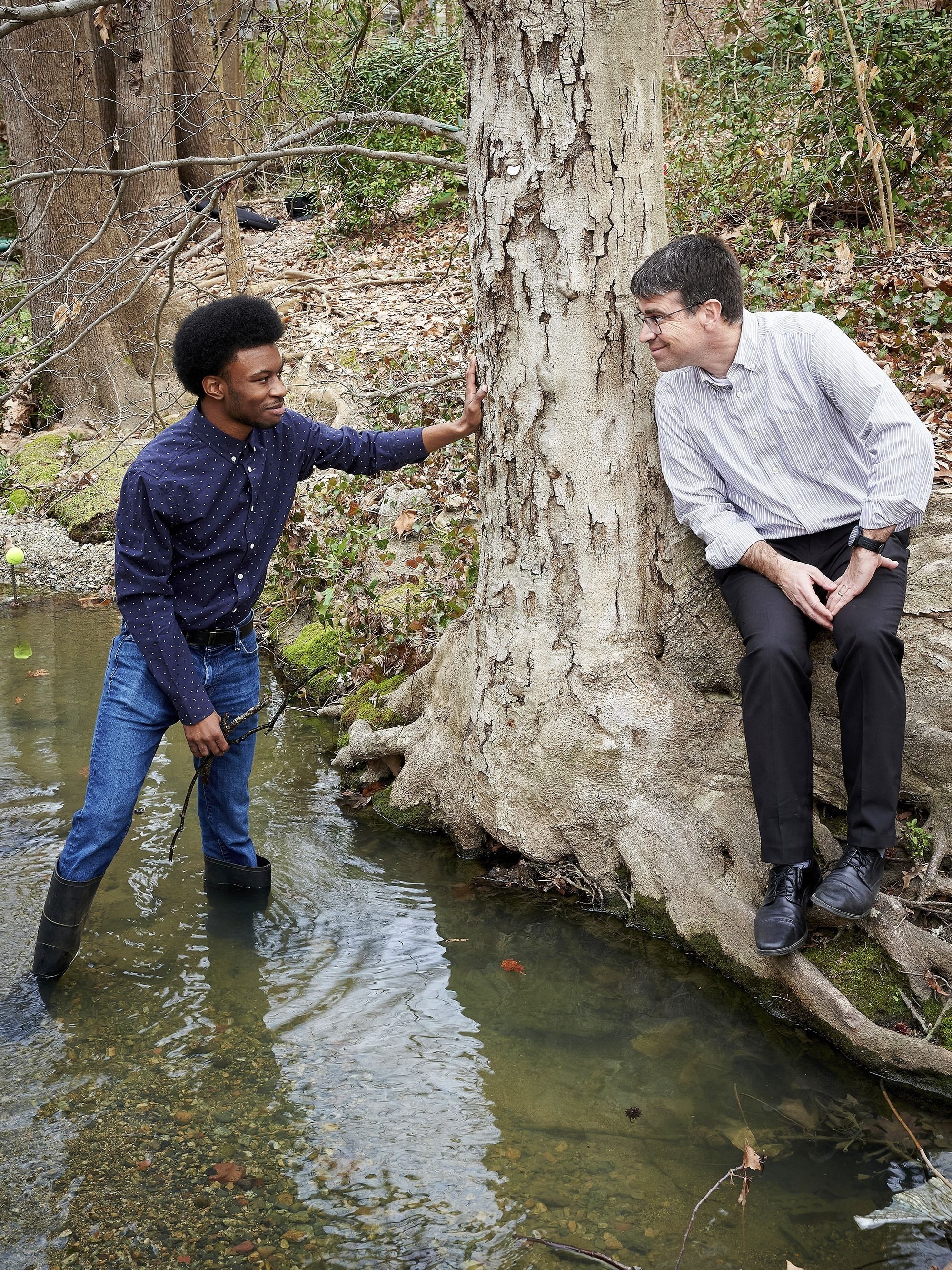 Chris Roberts, accompanied by faculty mentor Chris Oberlies, wades into a stream looking for fungal samples.
