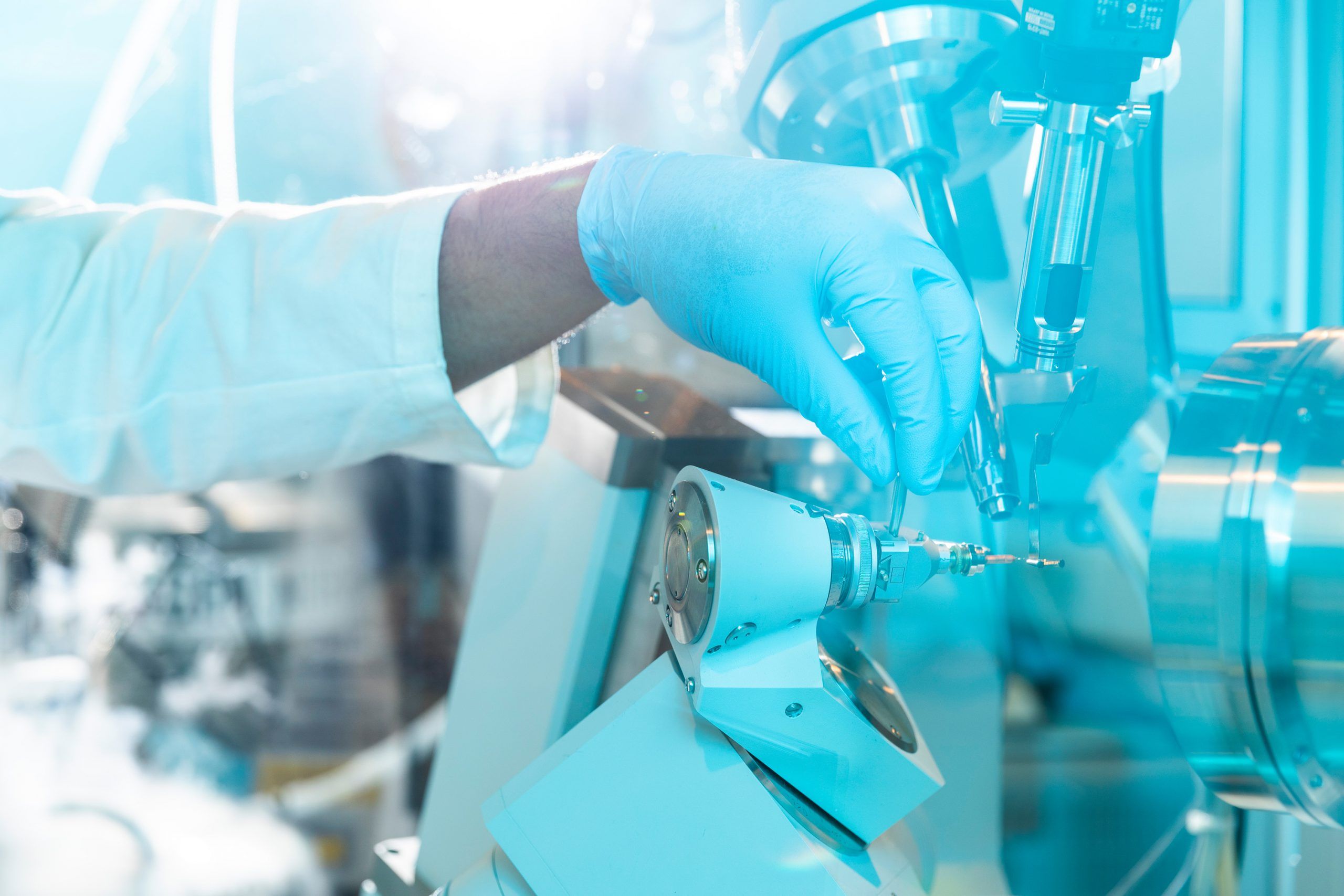 A close up of a hand in a protective glove placing an object into an x-ray crystallographer. 