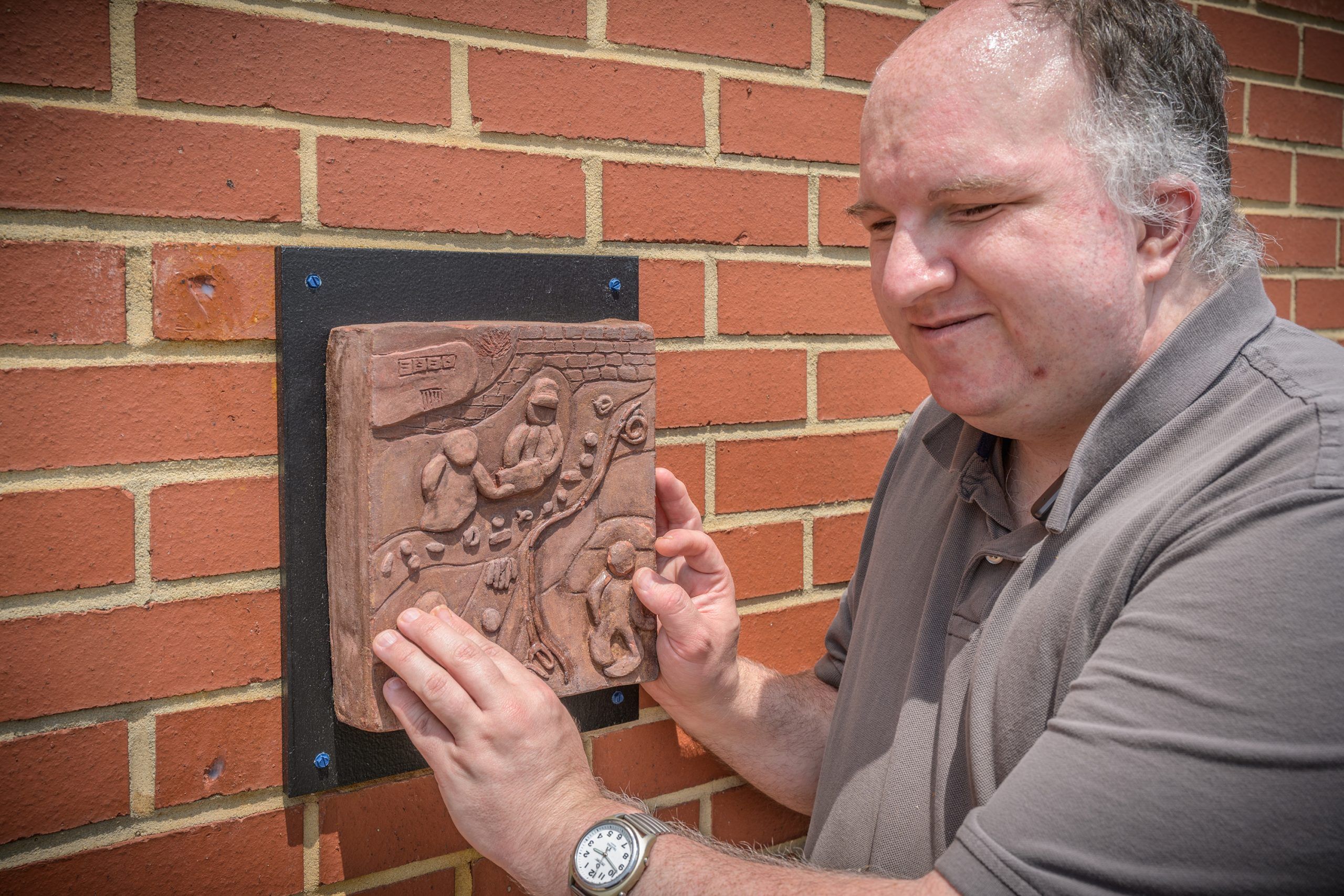 A blind man touching a ceramic art piece based on his story