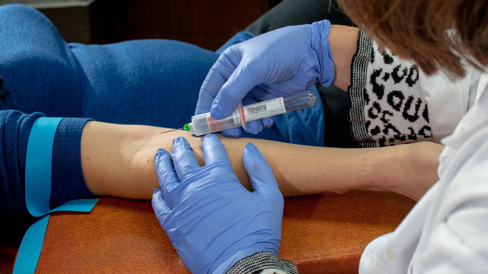 A researcher drawing blood from an adult