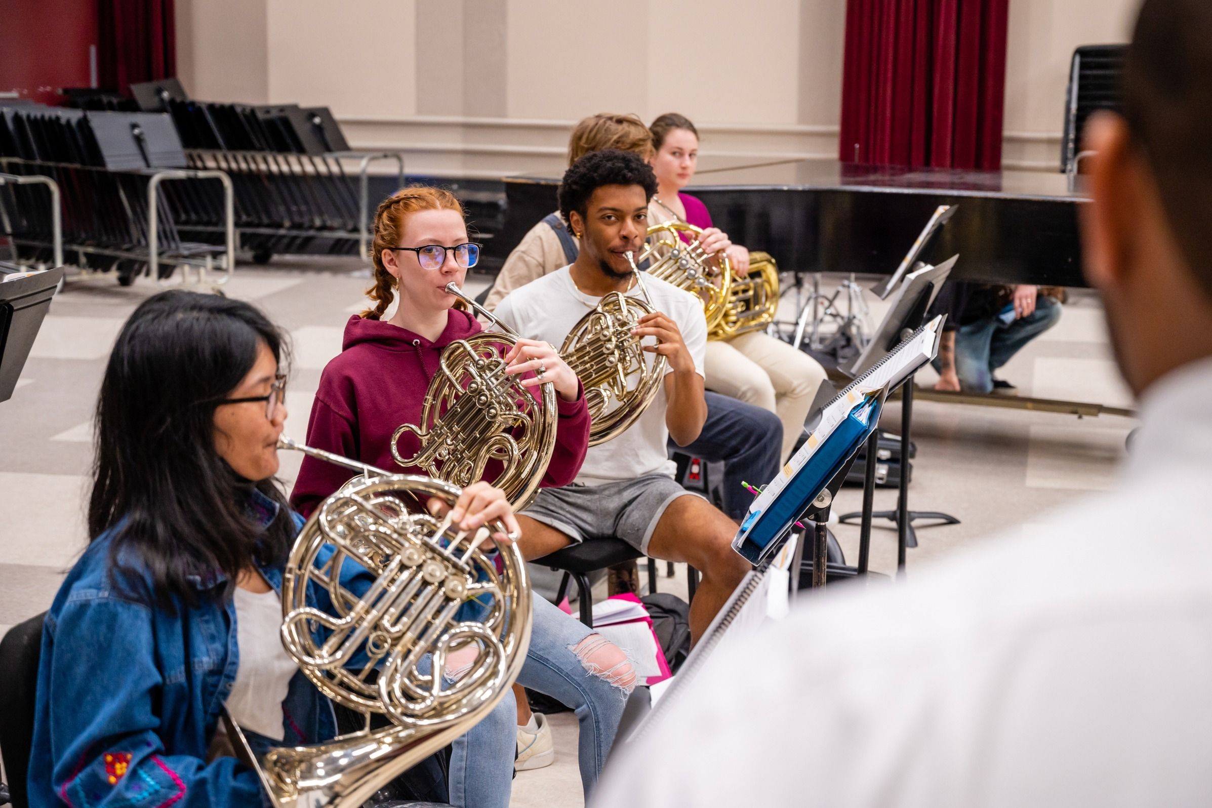 Three students playing French horns.