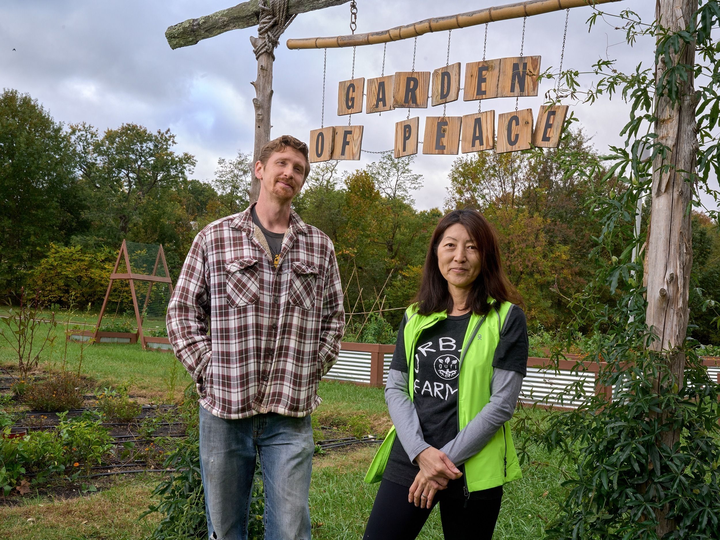 Dr. Etsuko Kinefuchi and Nathan Lewis stand under the Garden of Peace sign. 