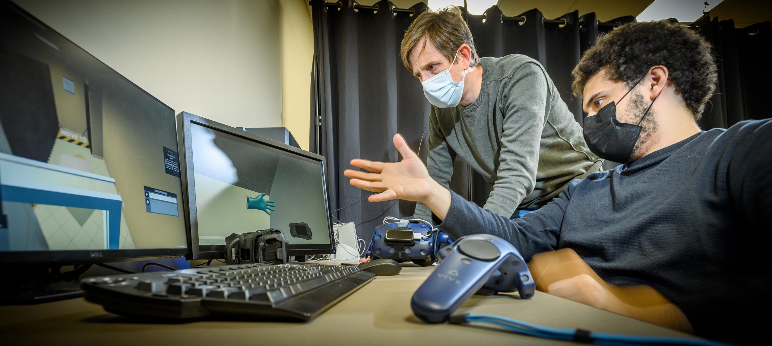 Dr. Kopper and student Kadir Lofca examine a VR interface build on a computer in the lab.