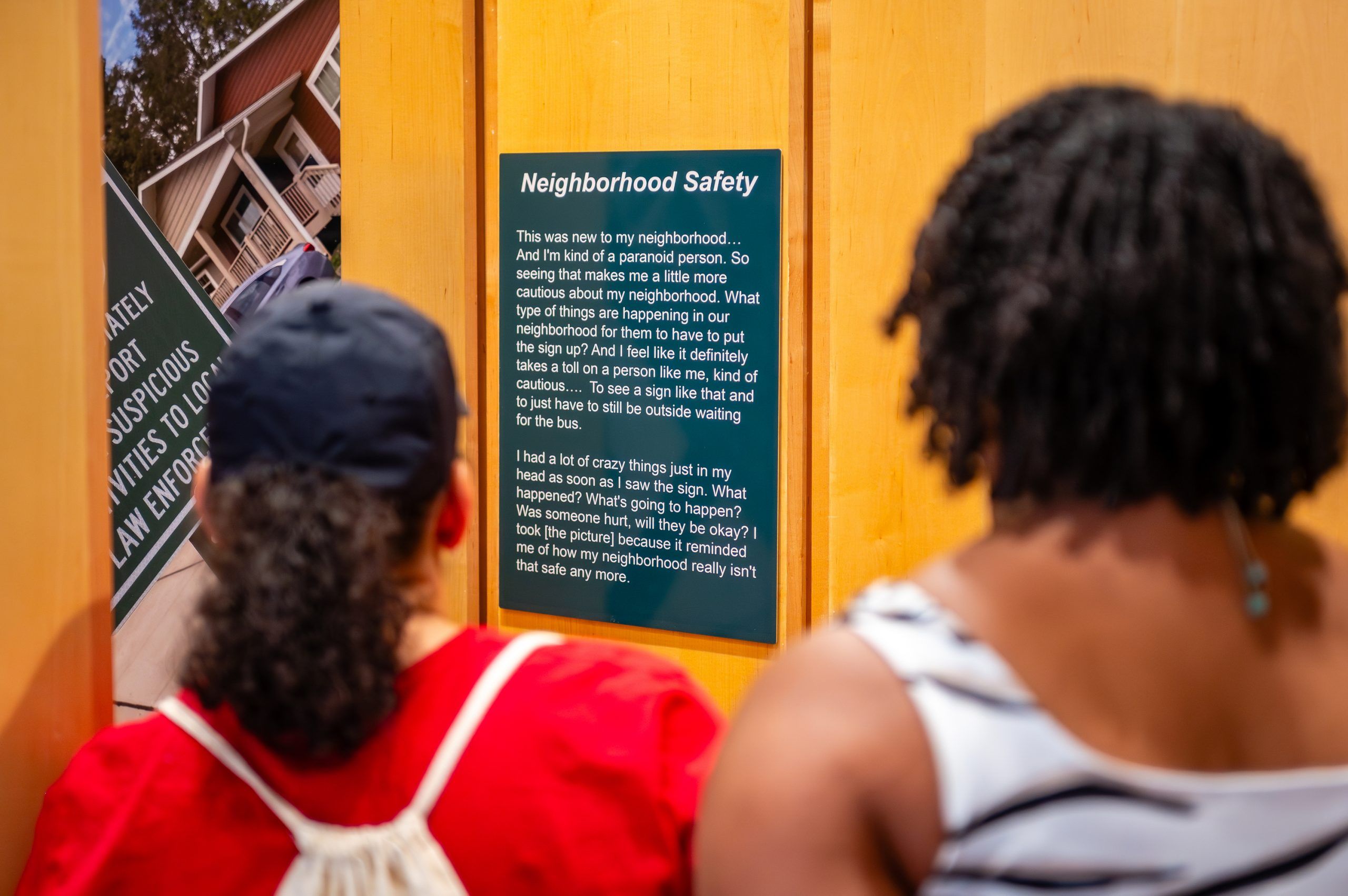 Two viwers looking at a piece titled "Neighborhood Safety"