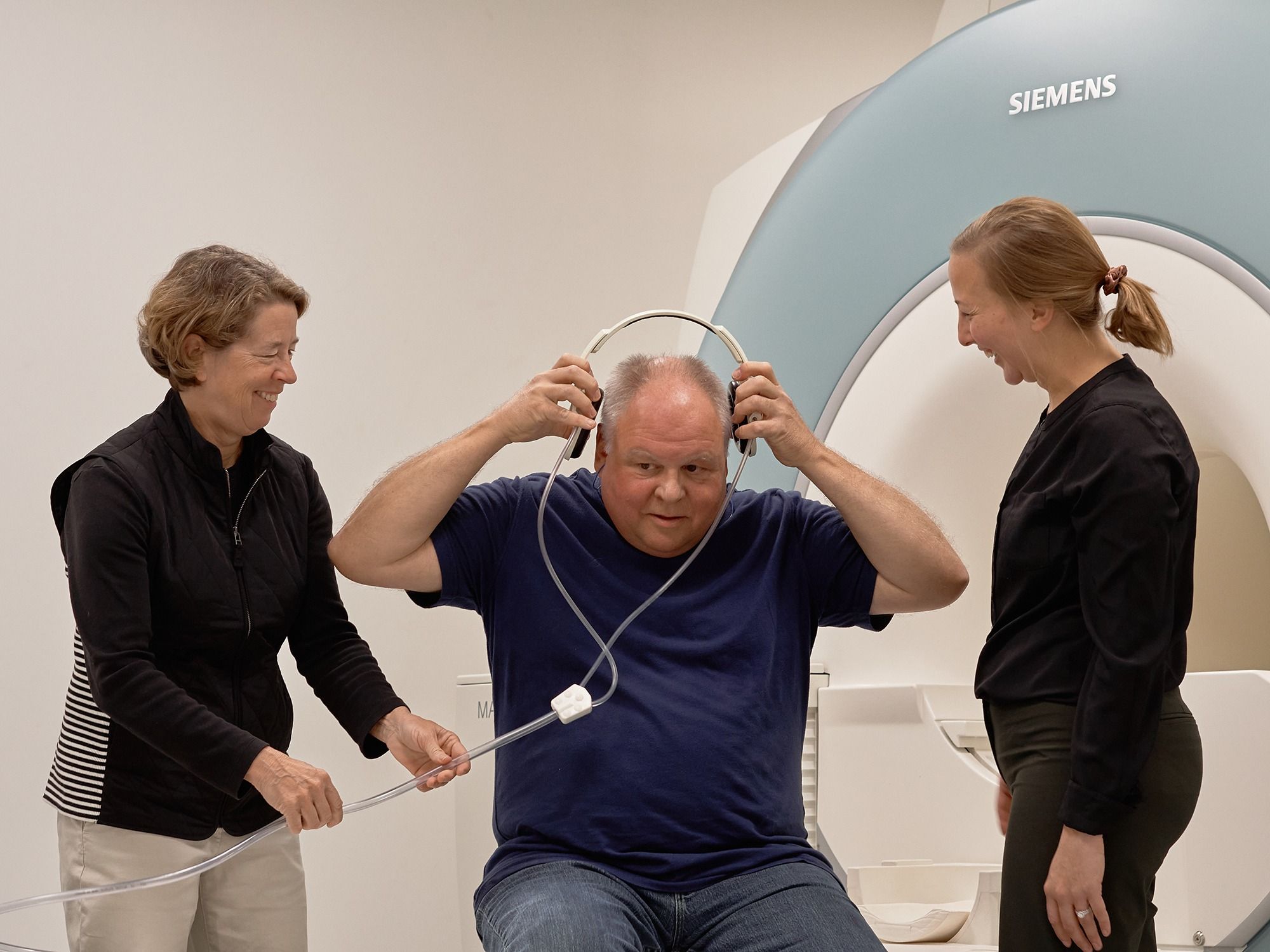 A research participant puts on headphones as Etnier and Ganesh prepare him for the MRI.