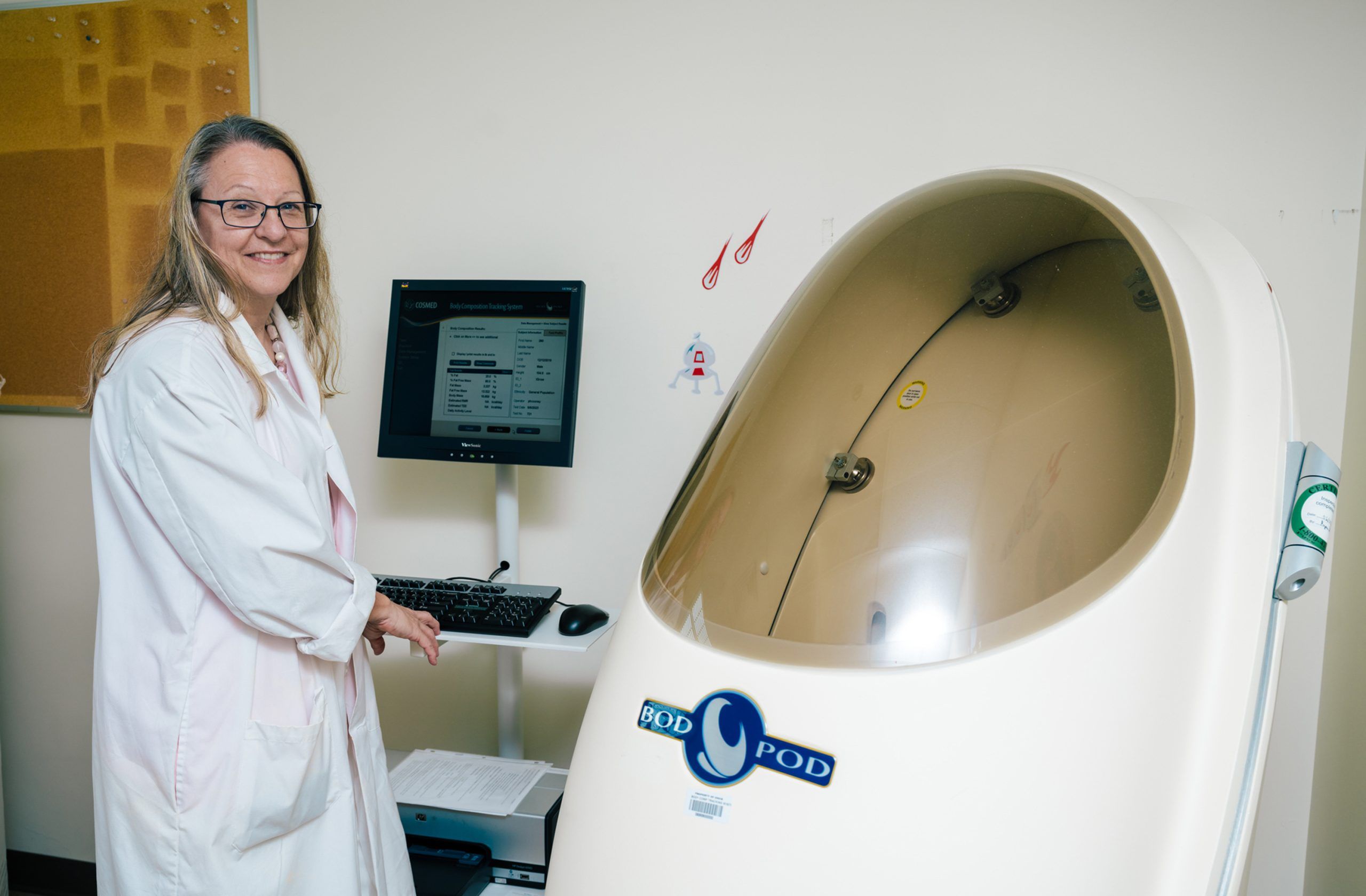 Wideman next to the Bod Pod, a machine that takes measurements of a child's body