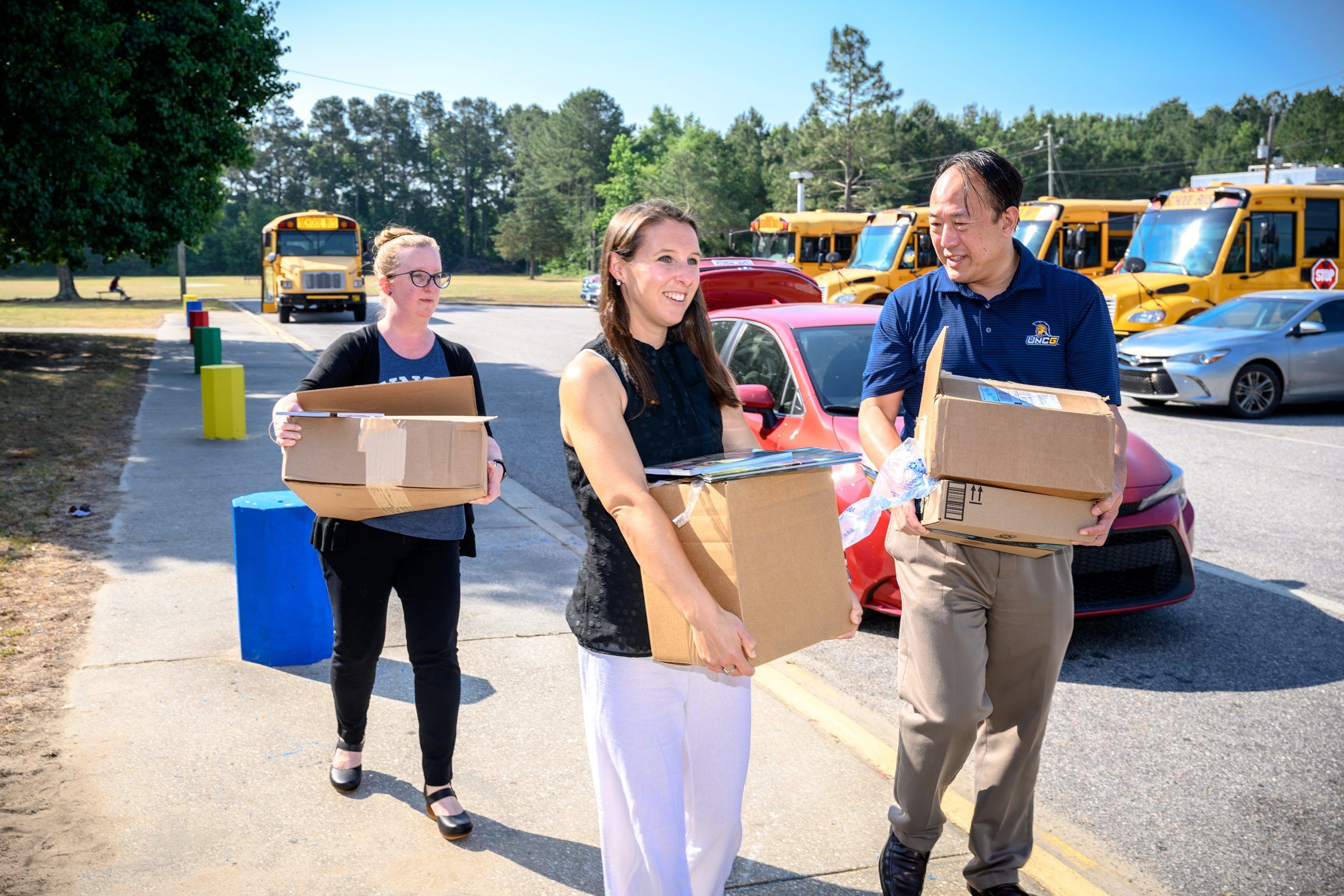 Chow and his team carrying boxes full of books into a school