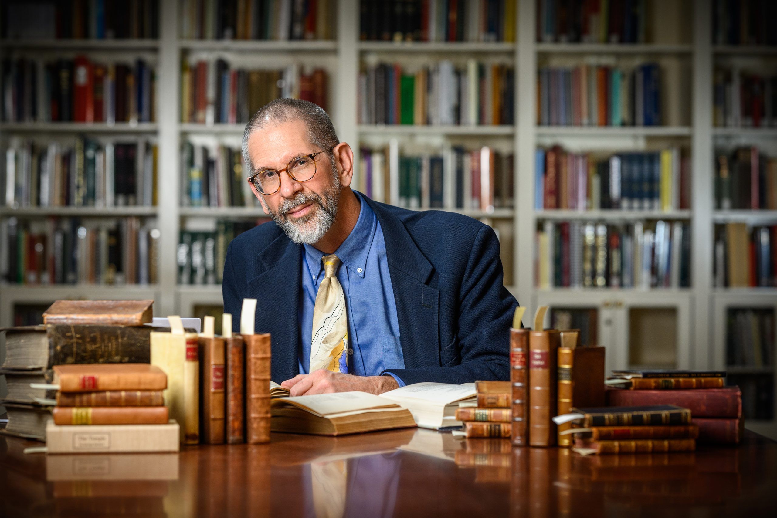 Dr. Chris Hodgkins sitting in a reading room with a portion of UNCG's George Herbert collection in front of him.