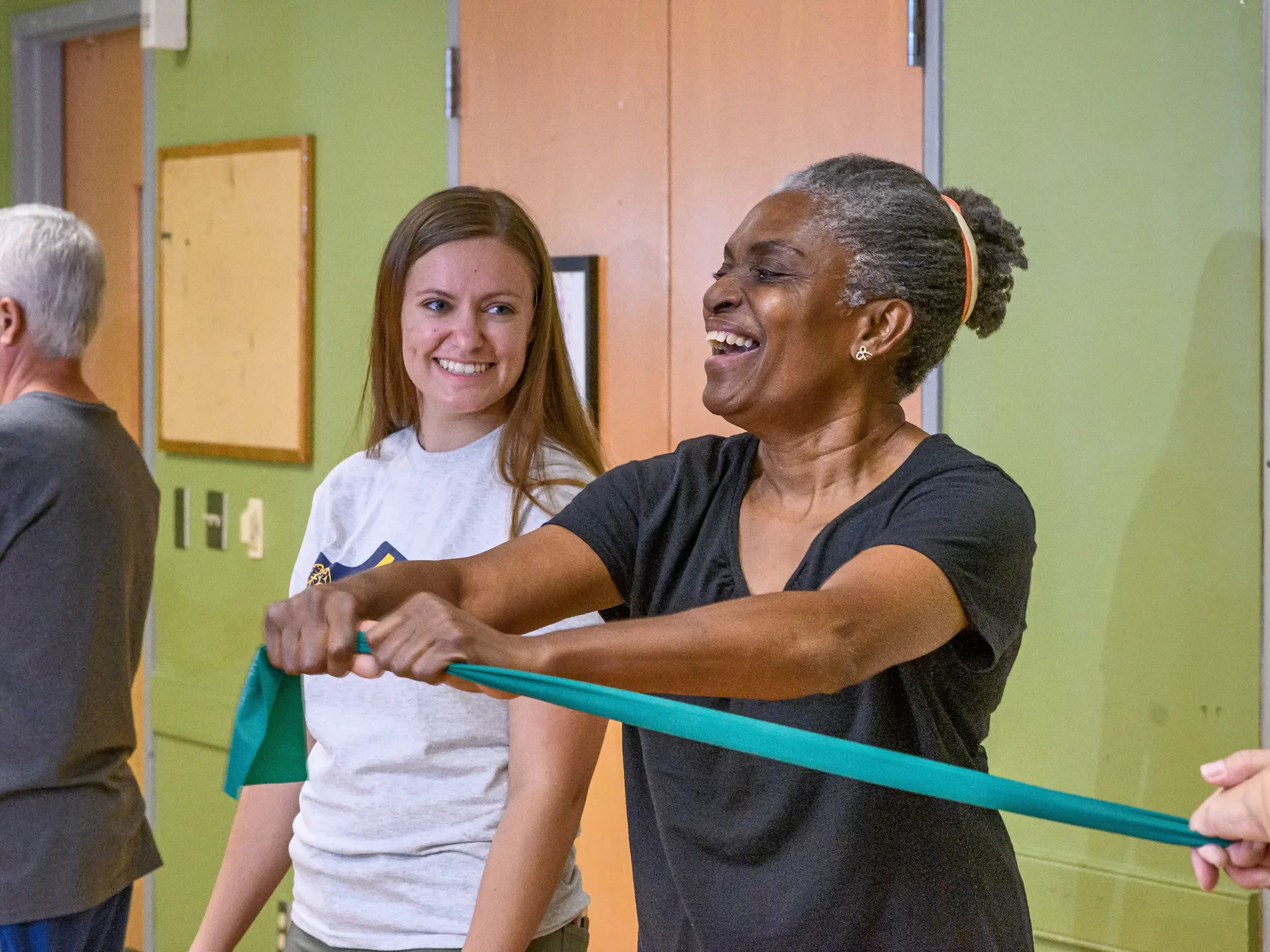 A patient stretching her arms using a green rubber band