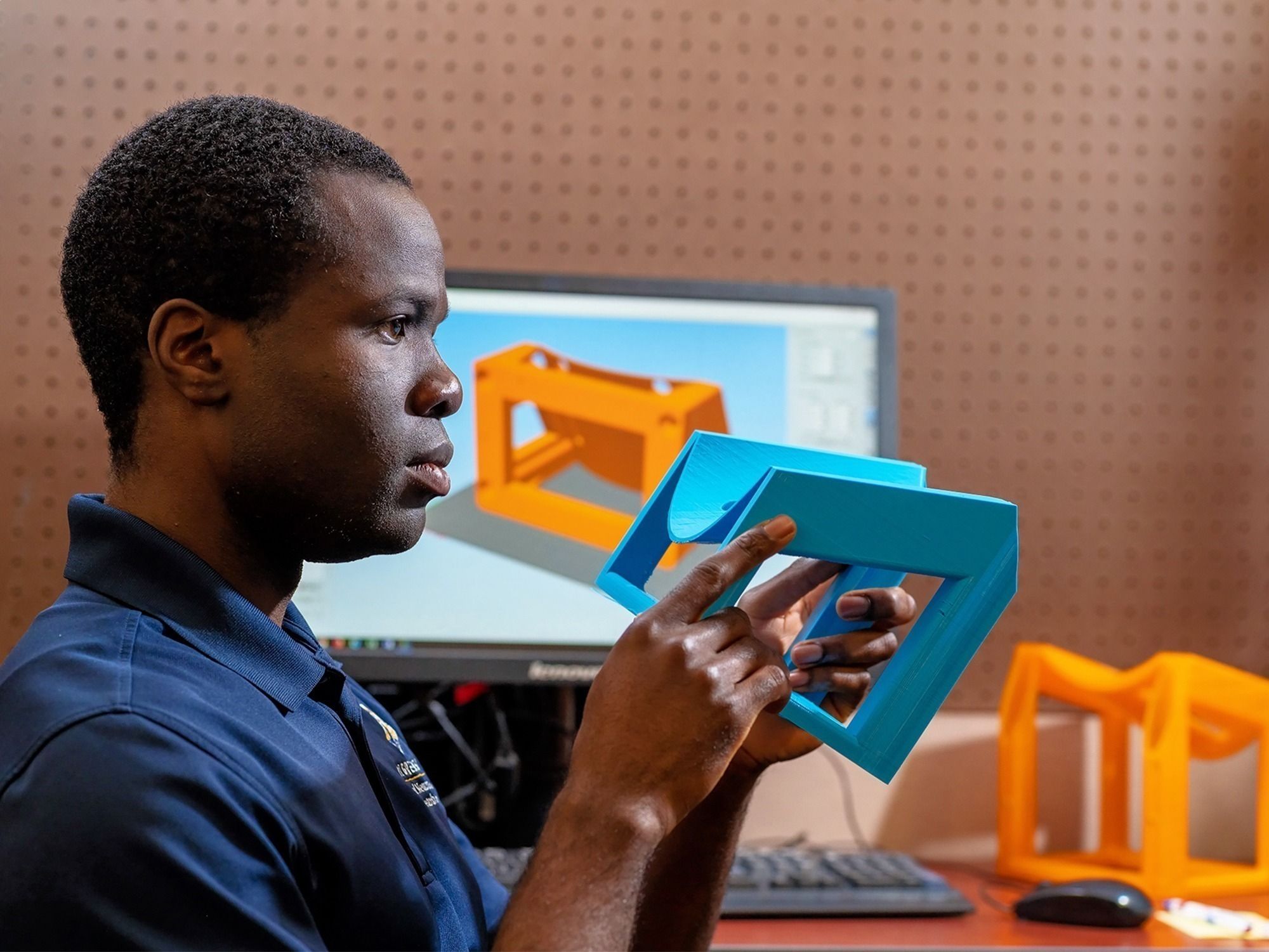 Grad student Elvis Foli examines a 3D printed prototype of a device for measuring knee laxity.