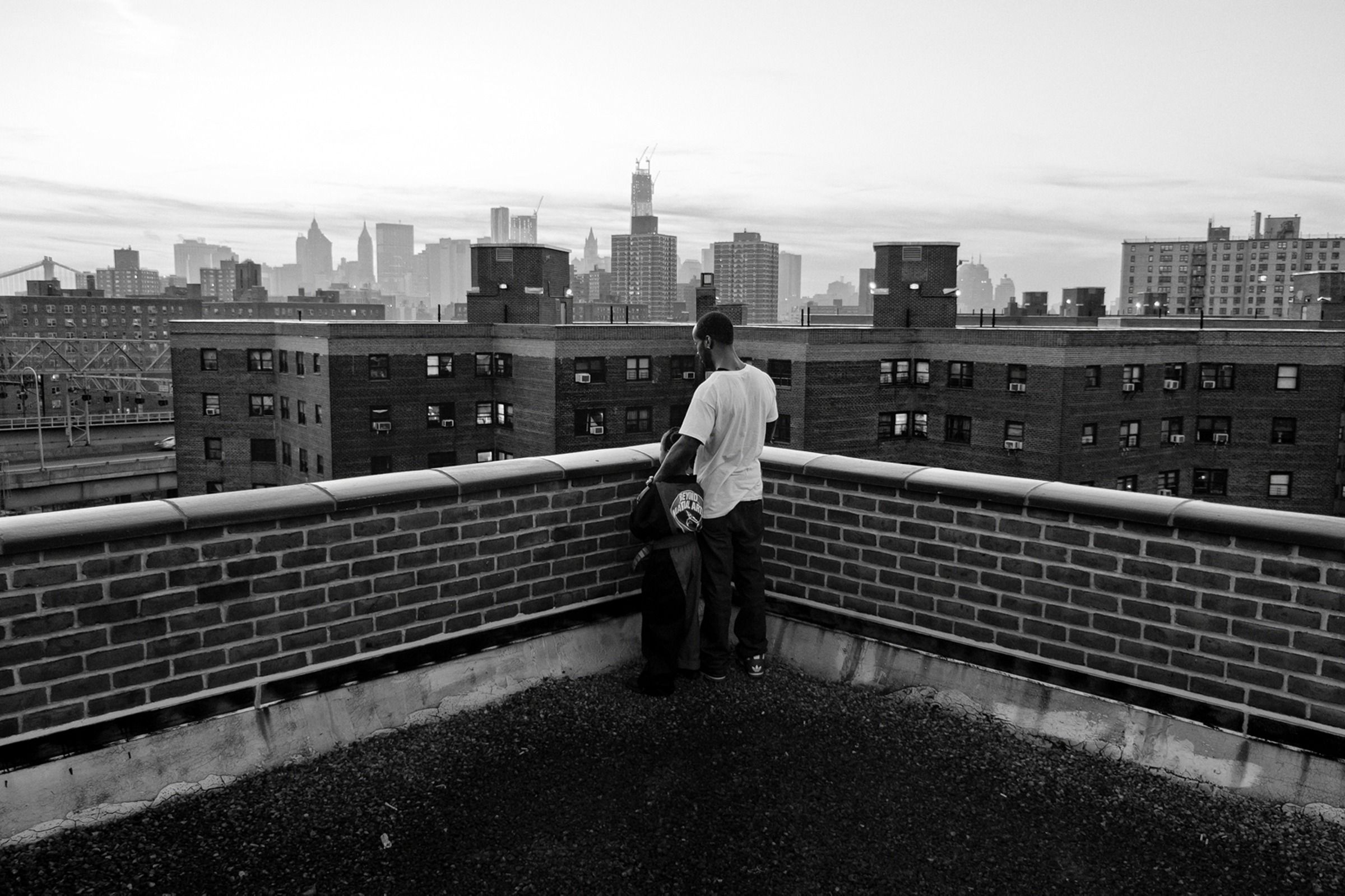 Father and son staring at East Baltimore on a roof