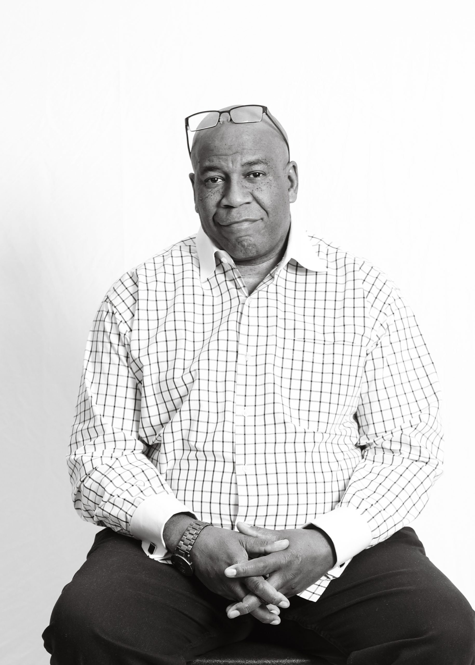 A black and white photo of a Black man with glasses on his forehead. 