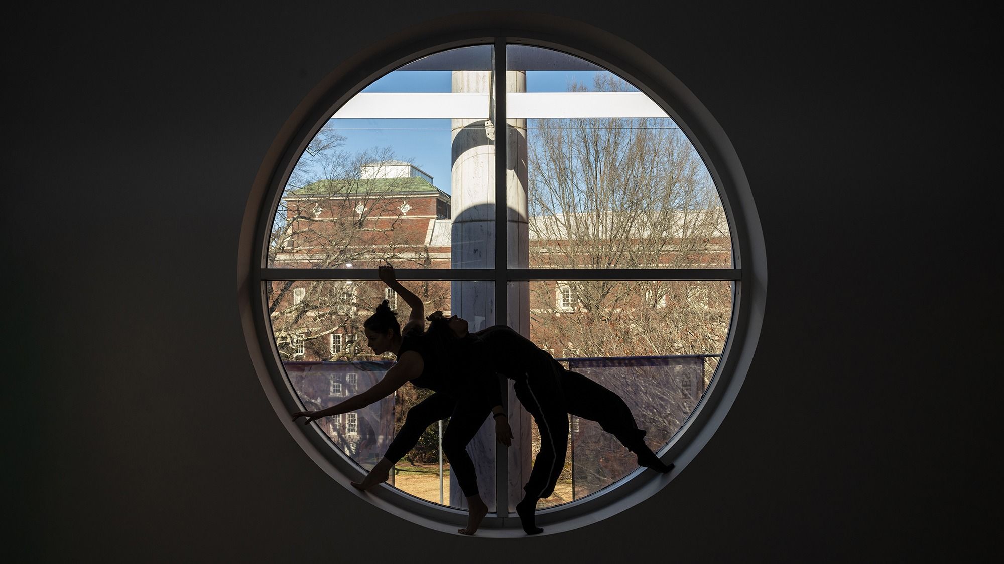 Two dancers silhouettes in front of a window