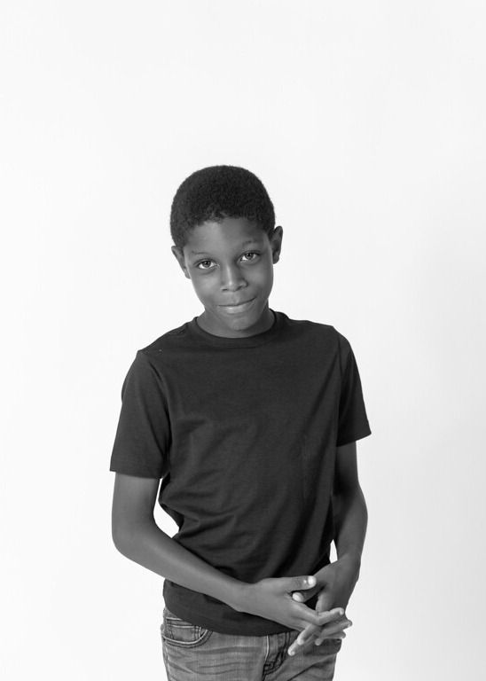 A black and white photo of a young black boy with short hair.