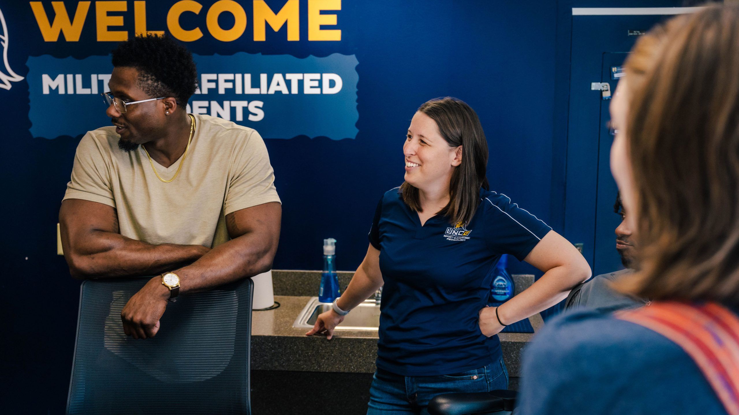 A person in beekeeping gear holding a rectangular object covered in bees
