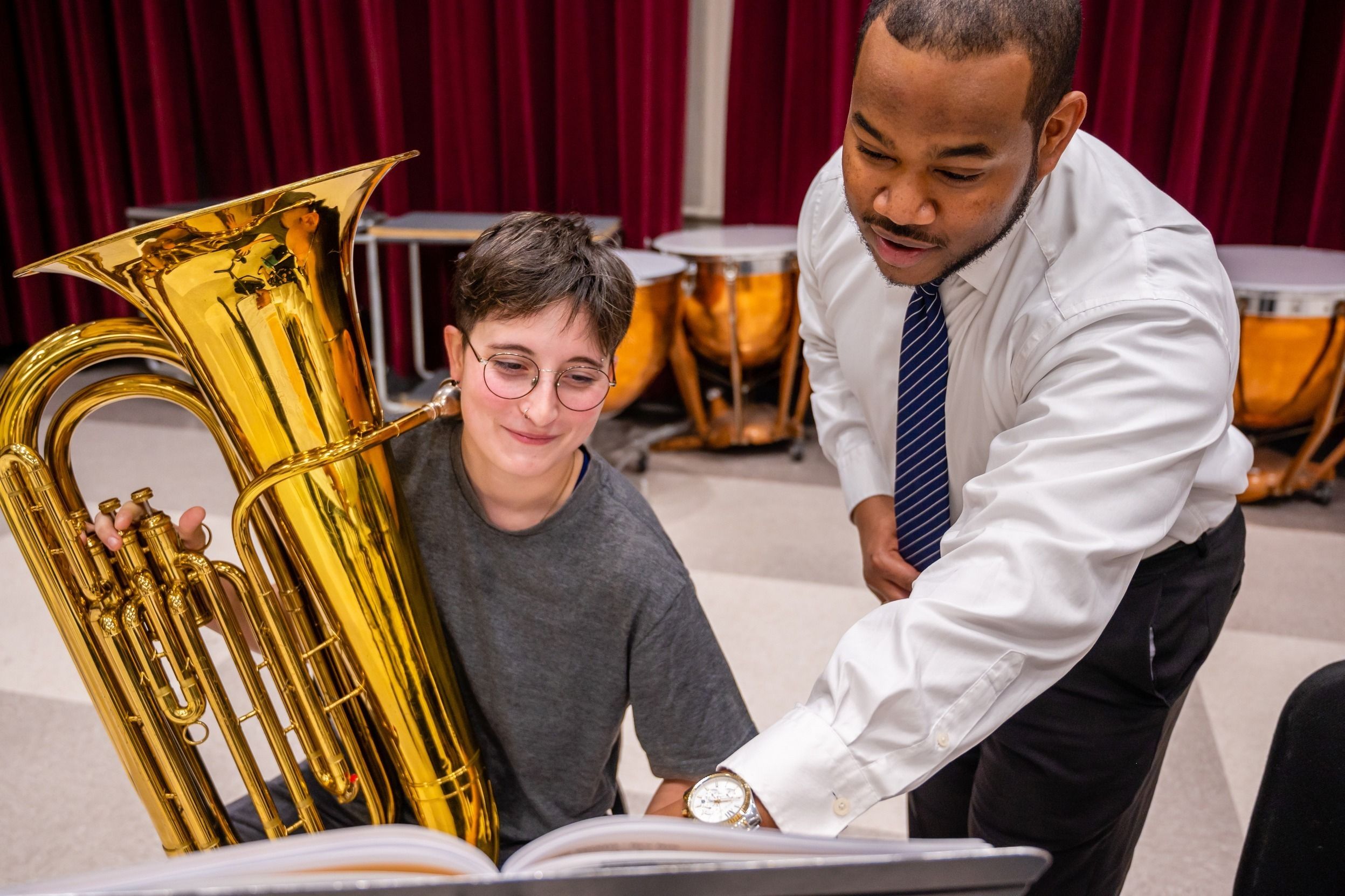 Dr. Parker going over sheet music with a student holding a tuba.