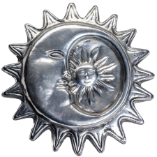 A silver Latinx art piece depicting the sun and moon