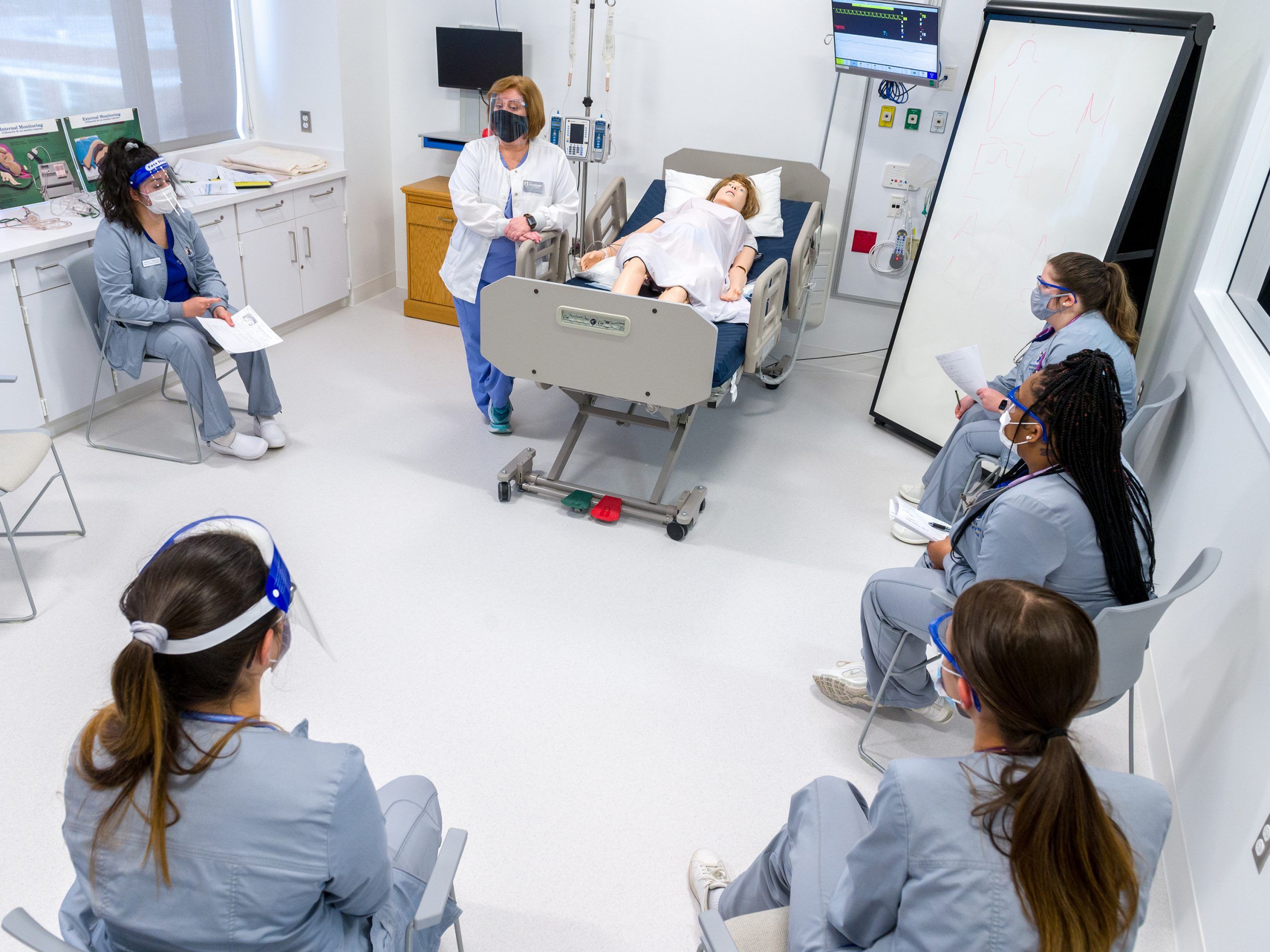Nursing students watch an instructor demonstrate on a model