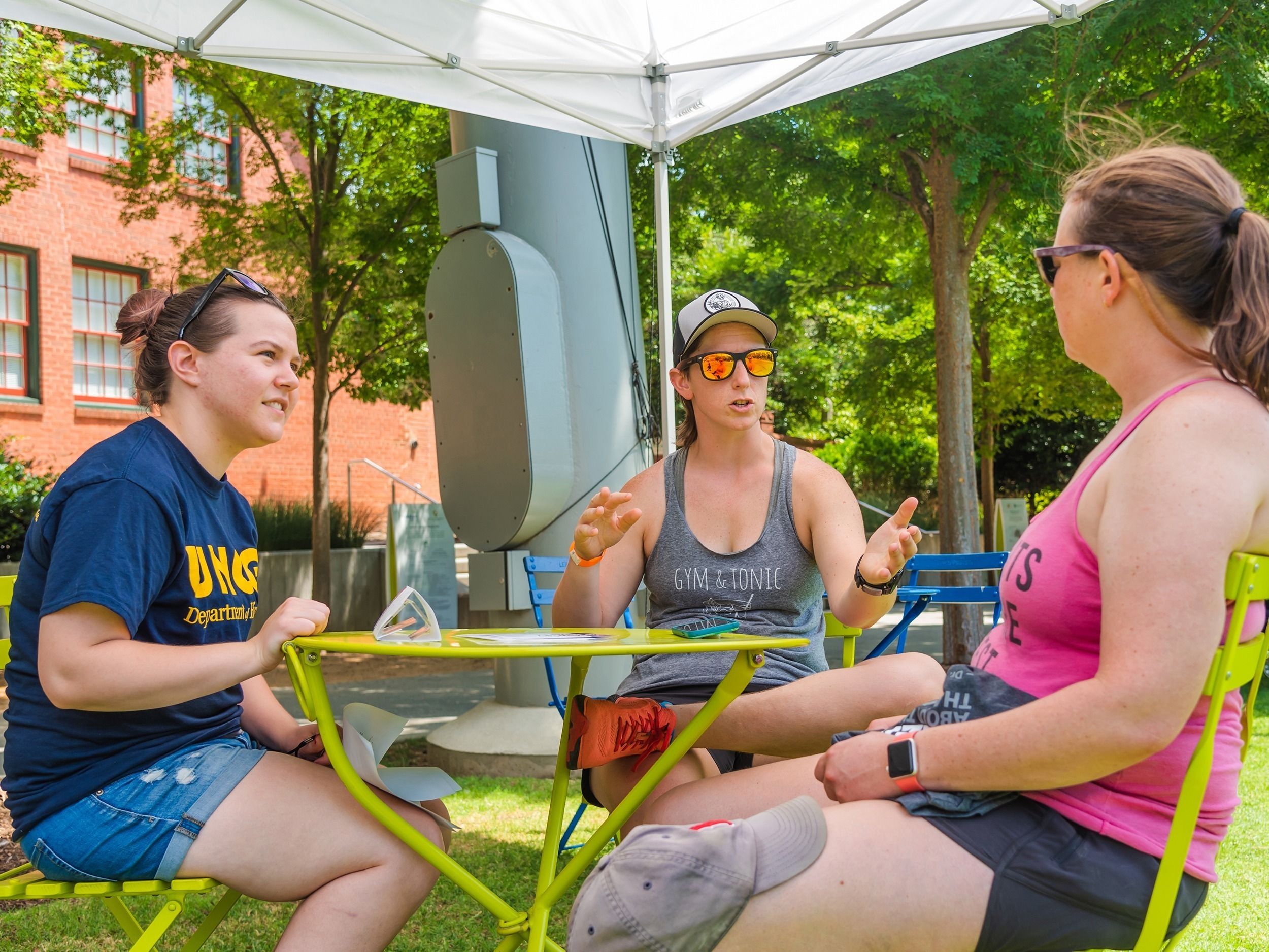 A student and two community members sitting at a table, engaged in discussion.