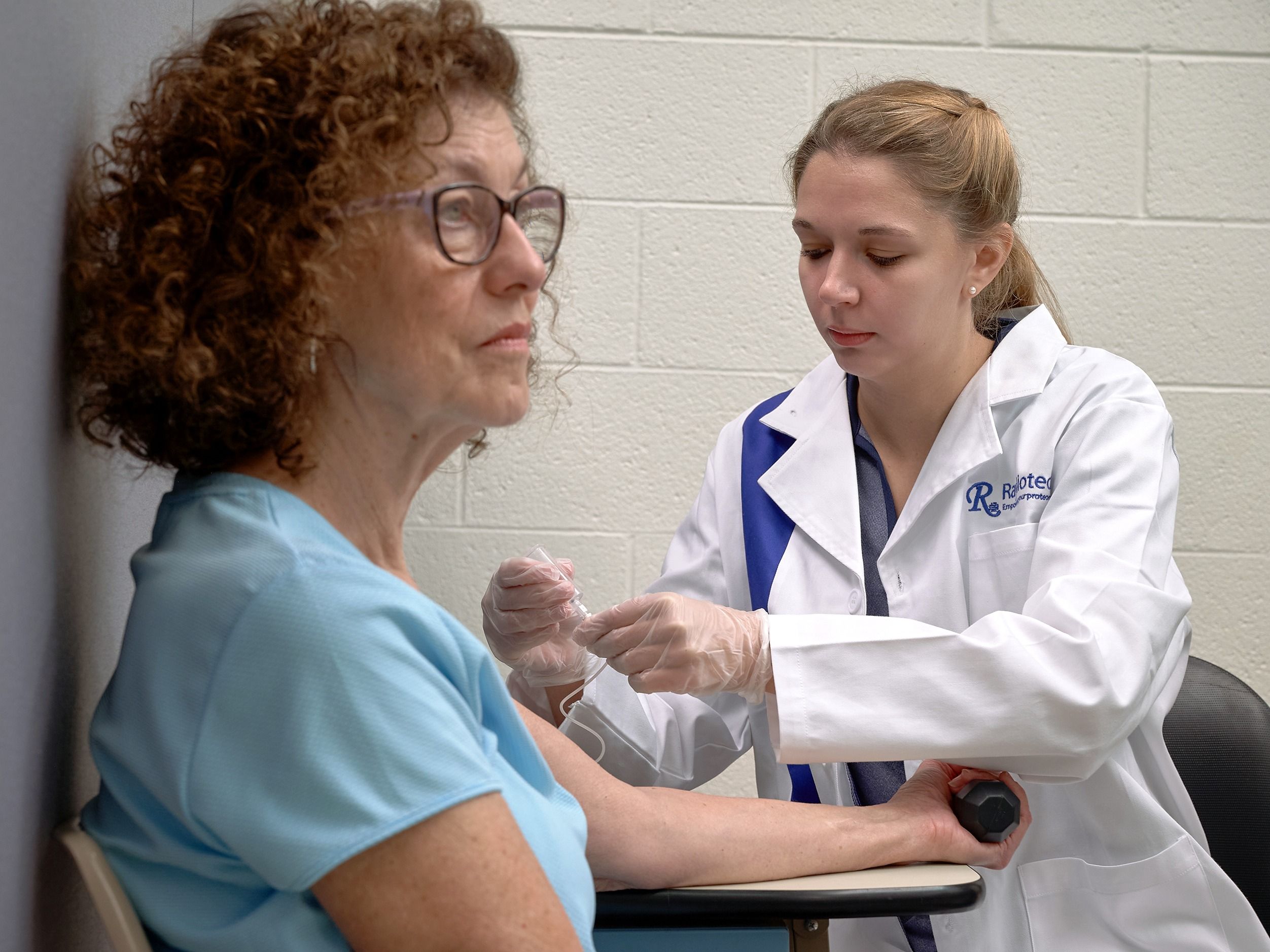 A postdoctoral student takes a blood sample from a research participant.