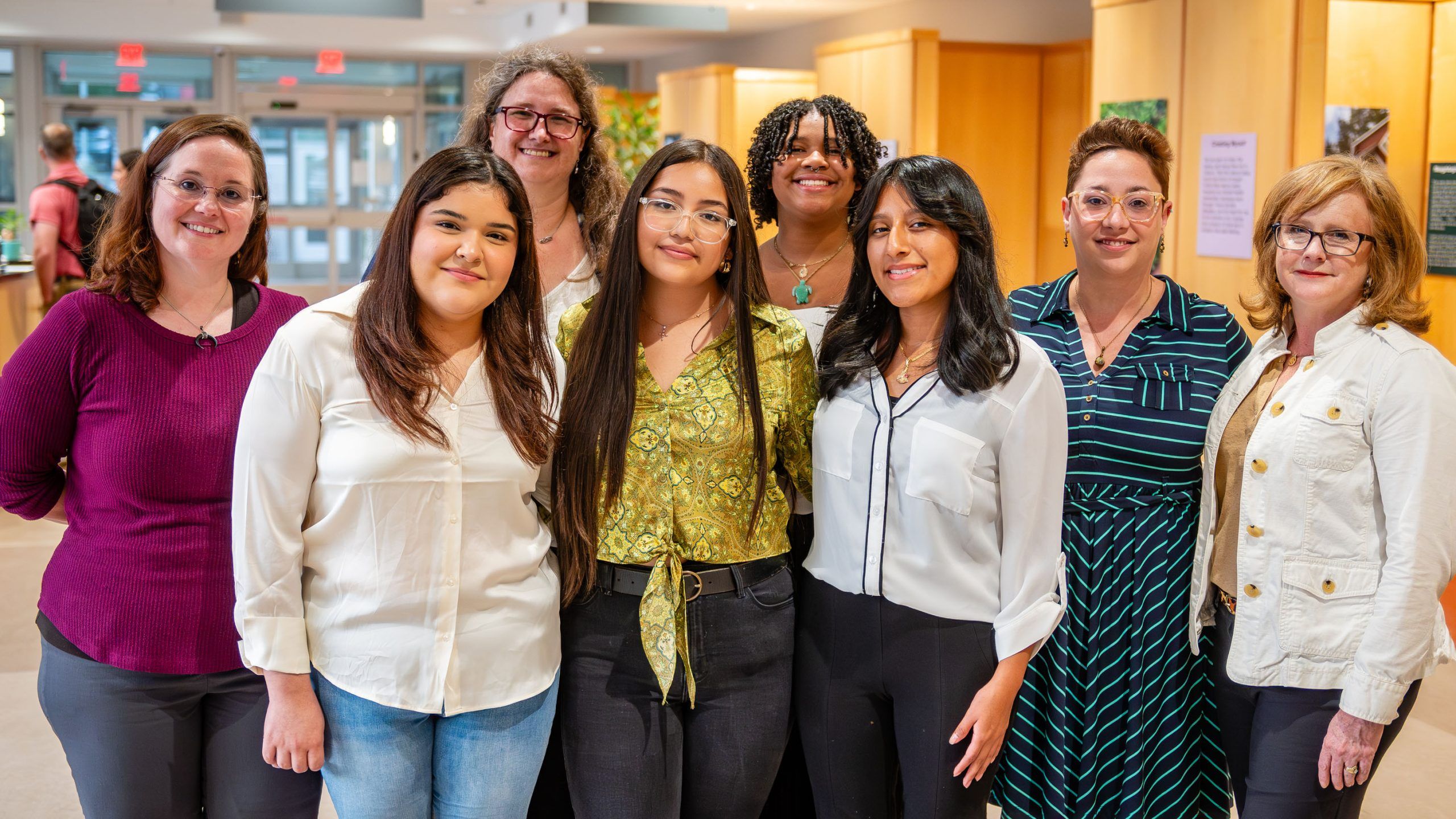 Grad student posing with teens at the photovoice exhibit she was in charge of
