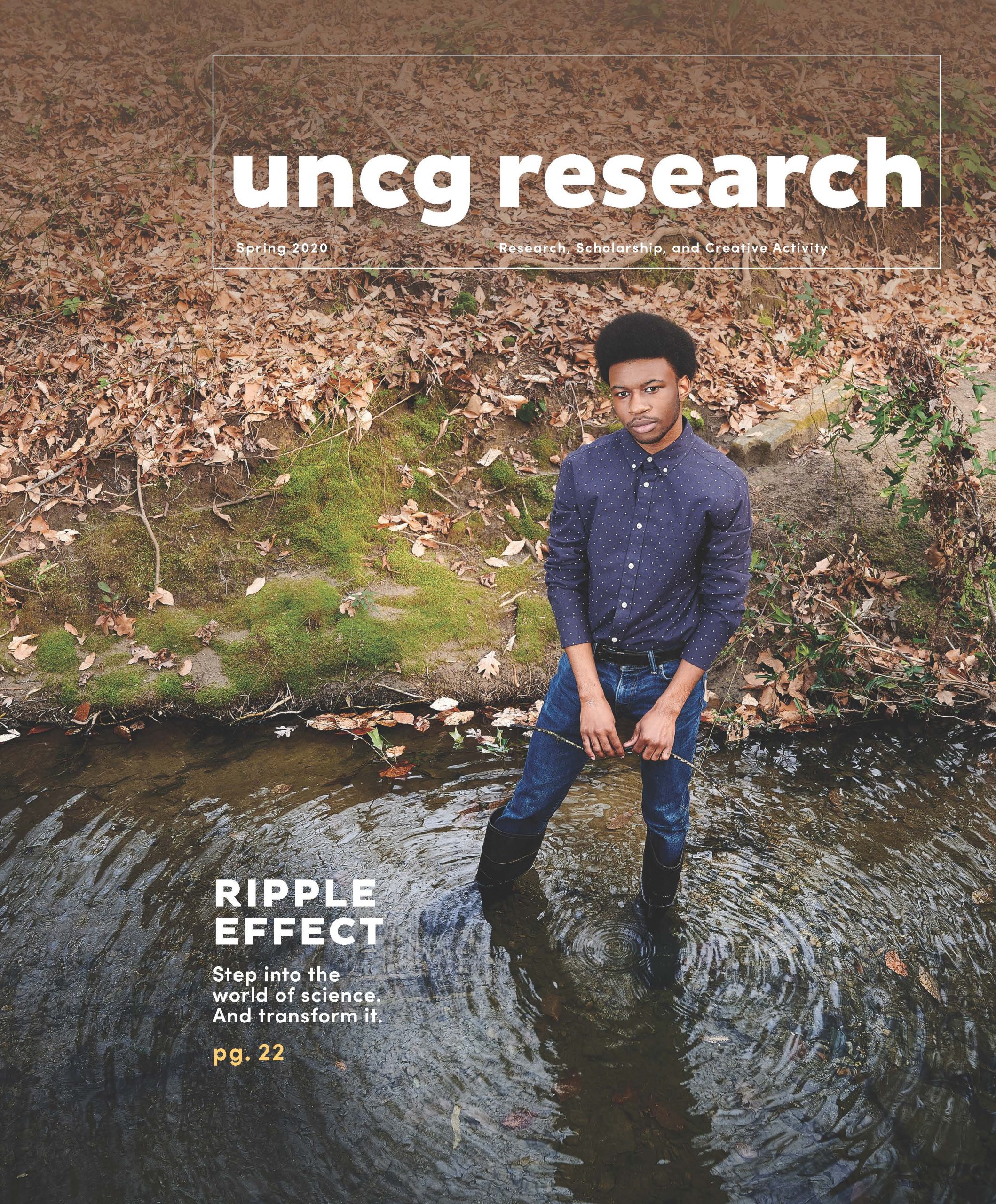 A man poses for a photo standing in a creek