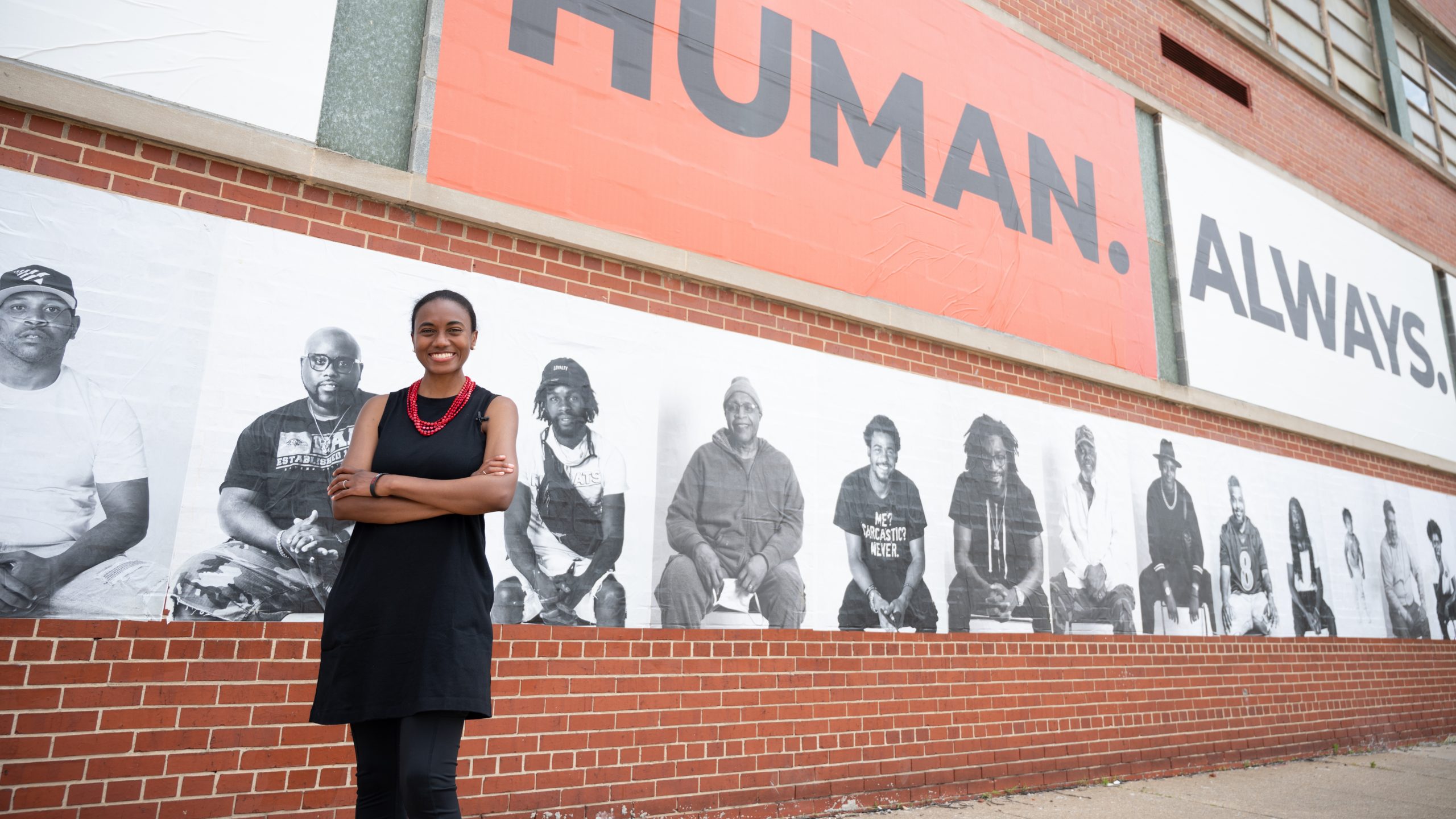 a woman standing in front of a mural and brick wall