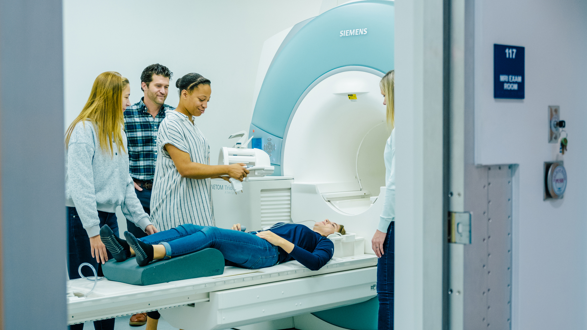 a person laying on an MRI bed with a group of people around