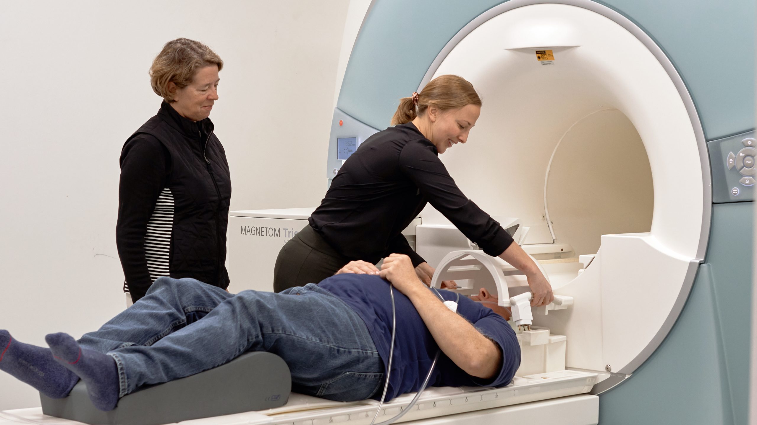 a person setting up an MRI device to a person