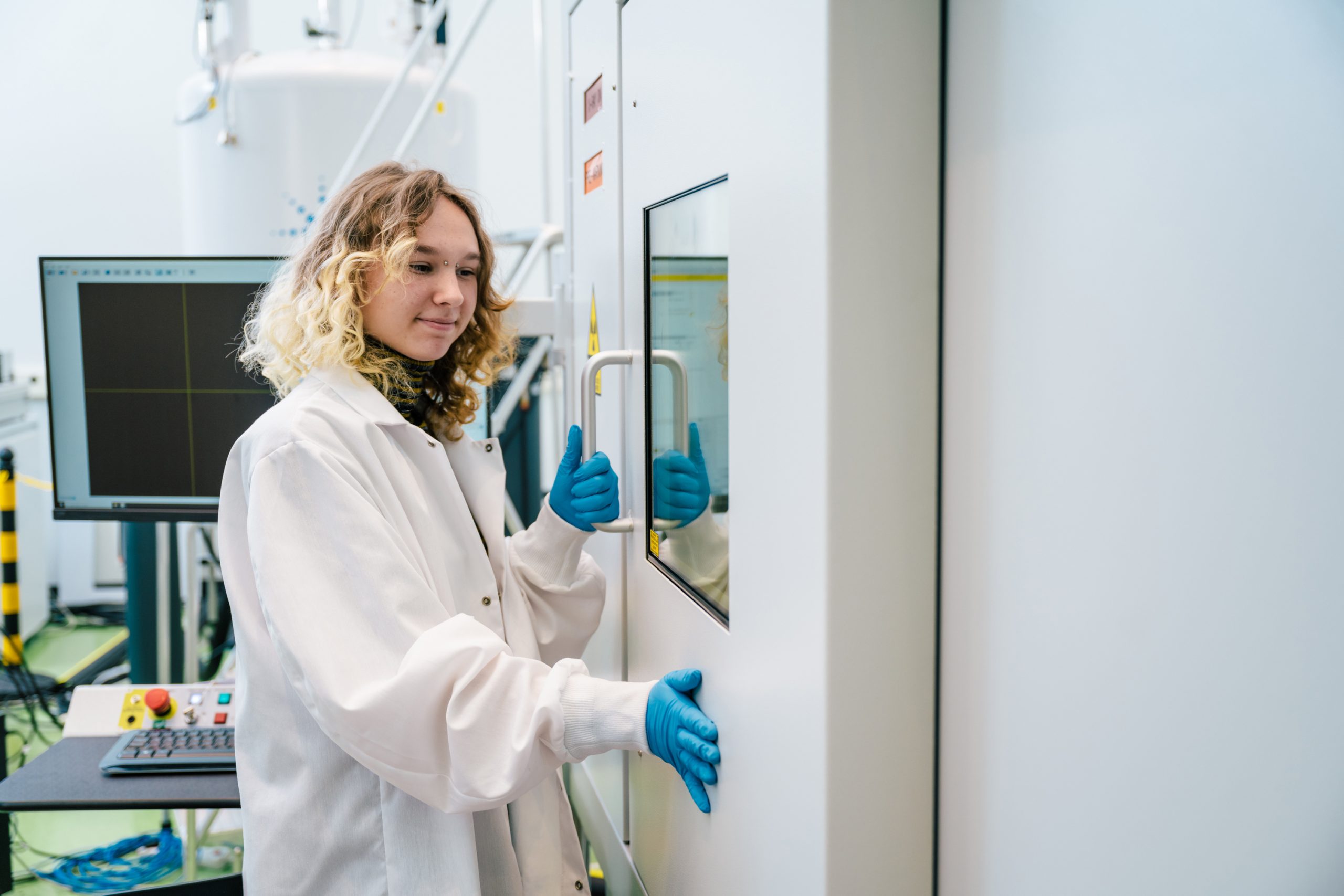 A person in a lab coat holding and pressing against a door