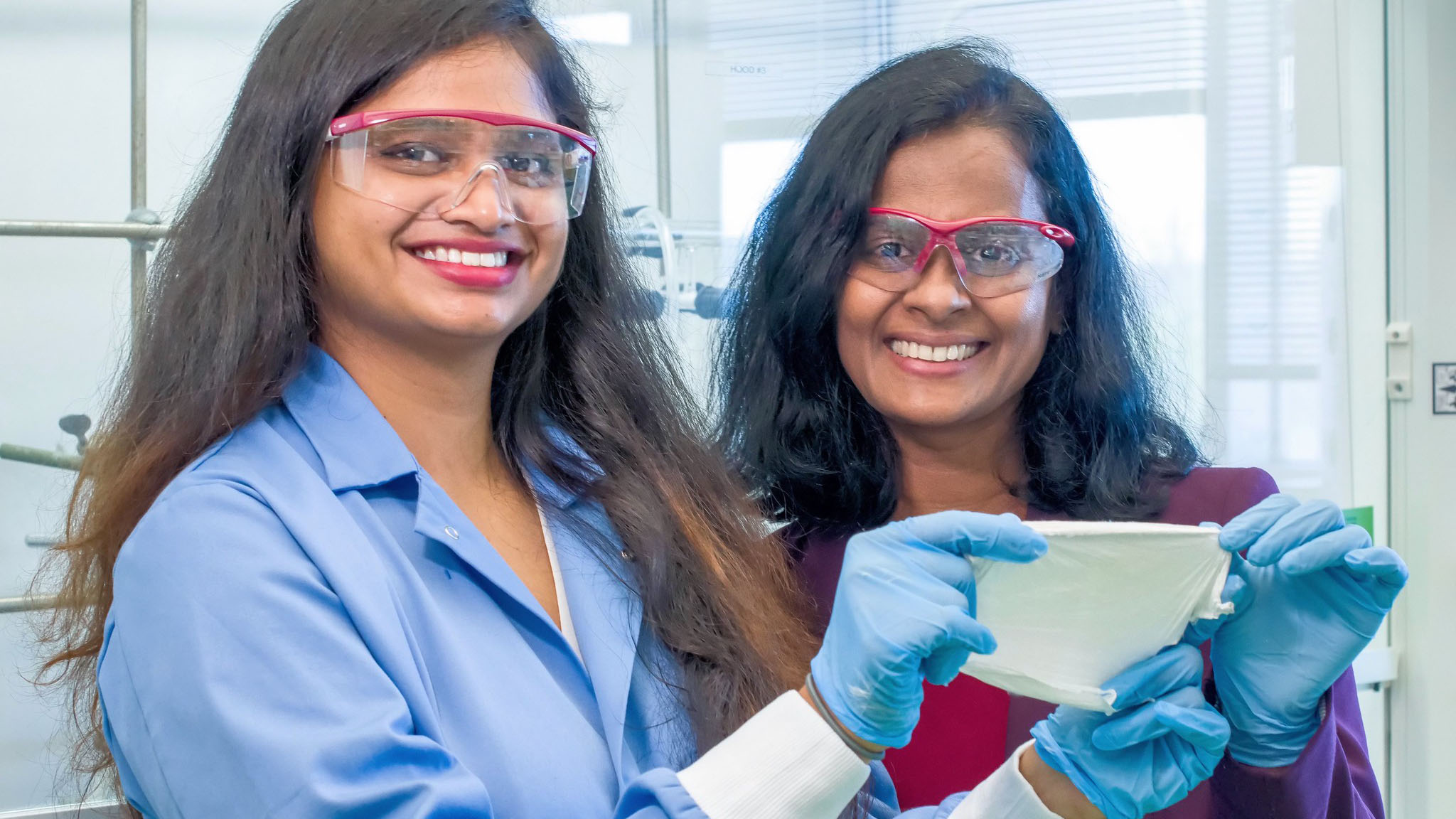 two women wearing safety glasses and gloves
