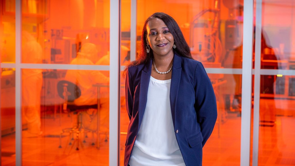 a woman in a blue jacket standing in front of an orange glowing room
