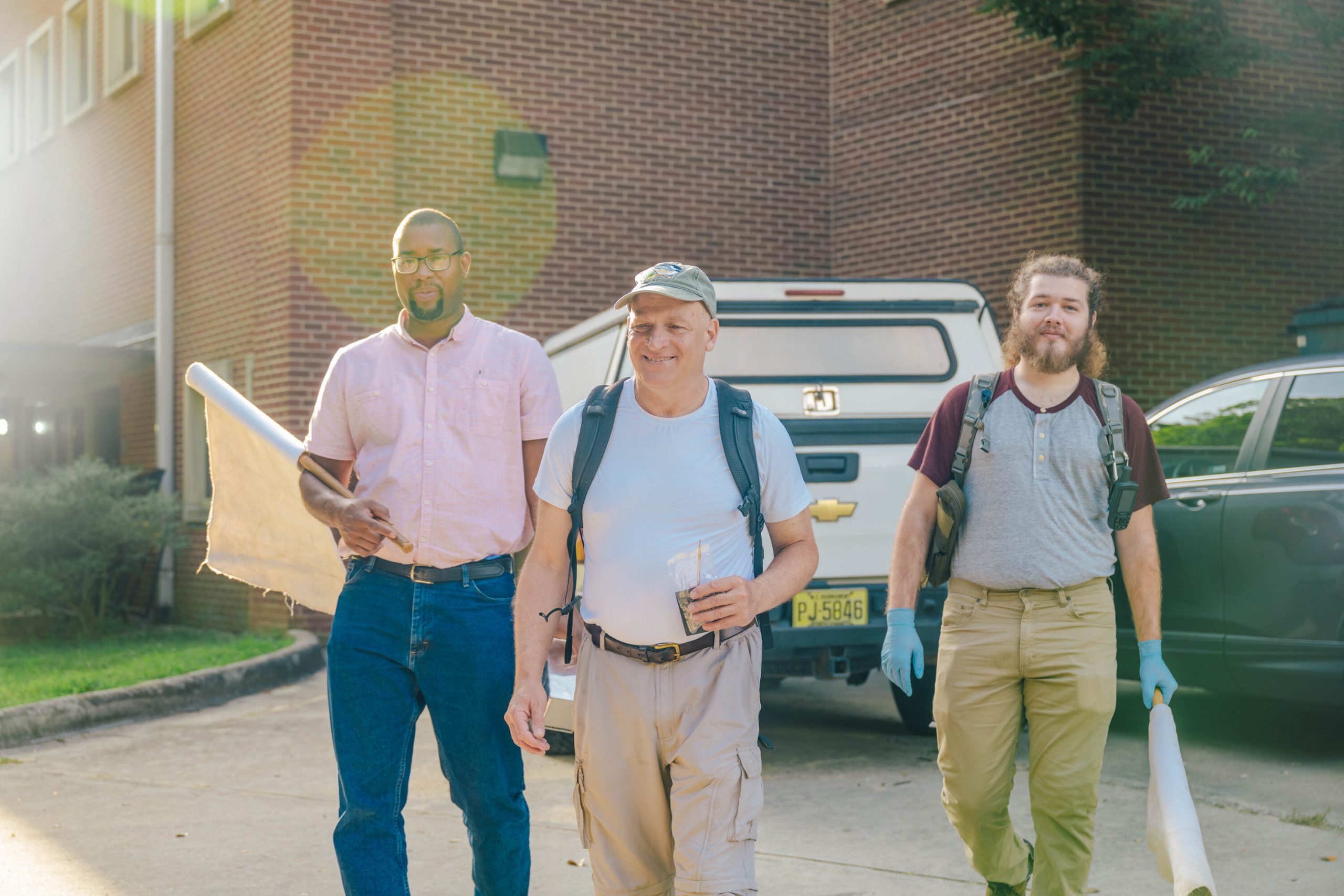 Gideon Wasserberg, Noah Holland, and Reuben Garshong leaving campus with equipment for field research