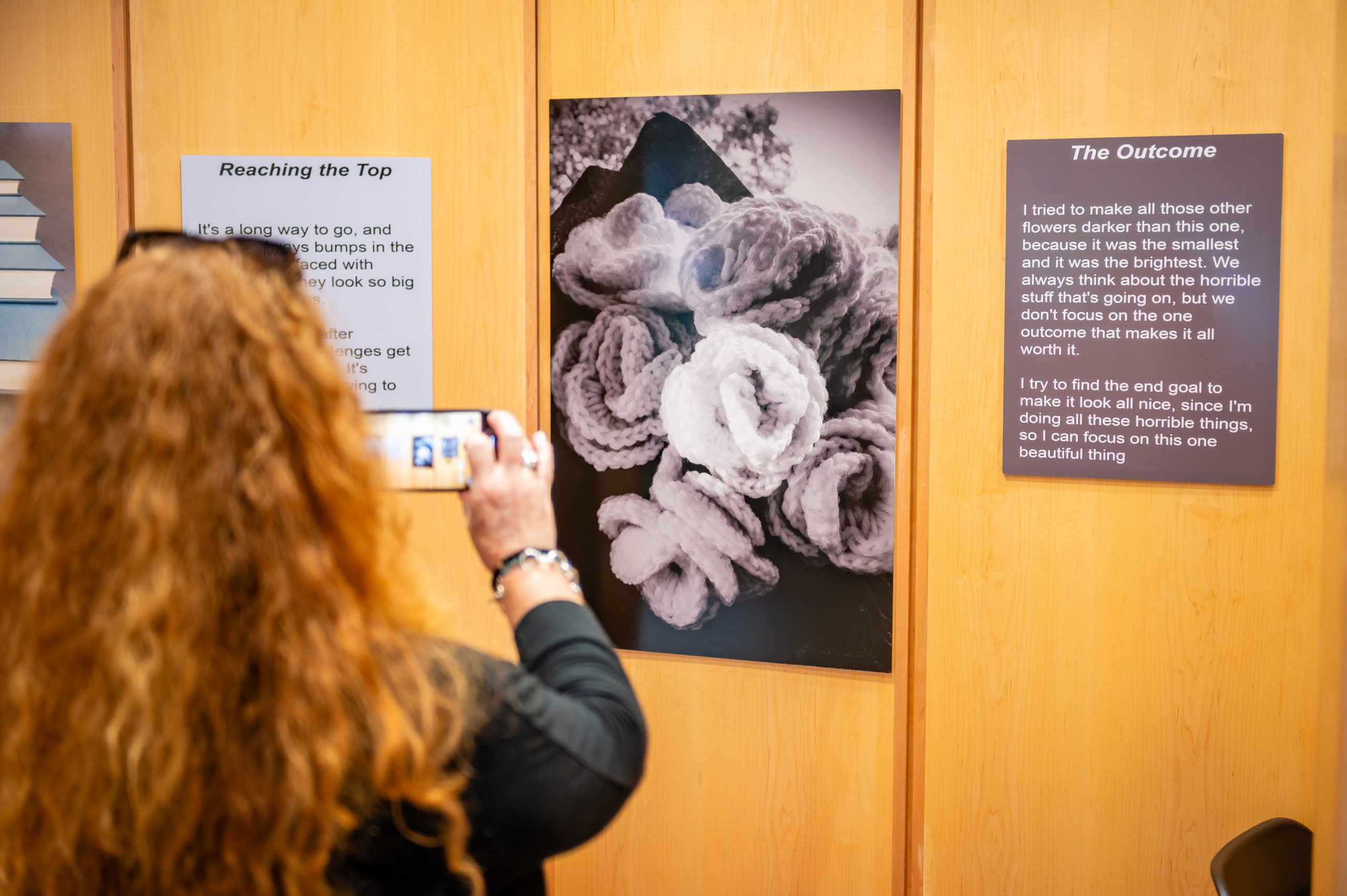 Person taking picture of student artwork "The Outcome"