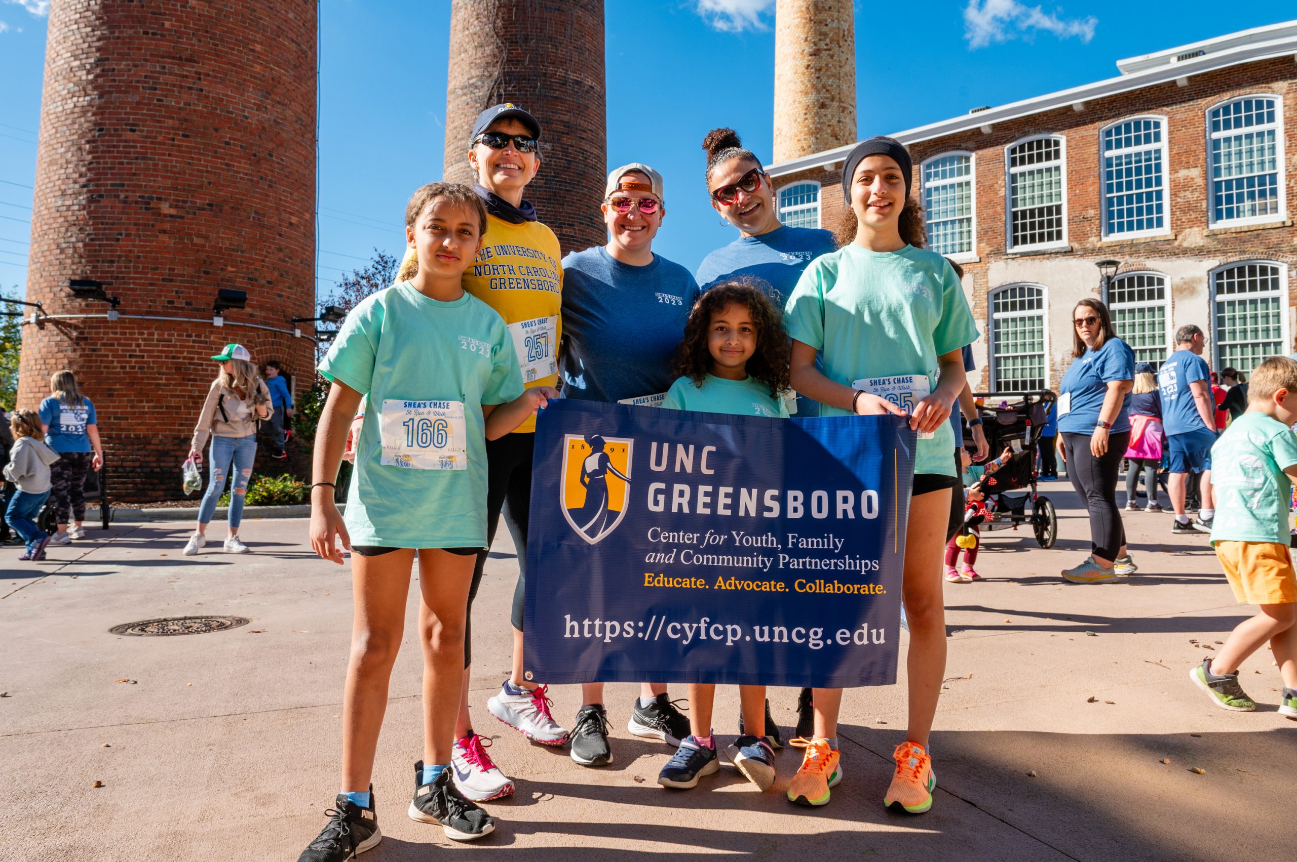 Members of the CYFCP at Shea's Chase 5k holding UNCG banner
